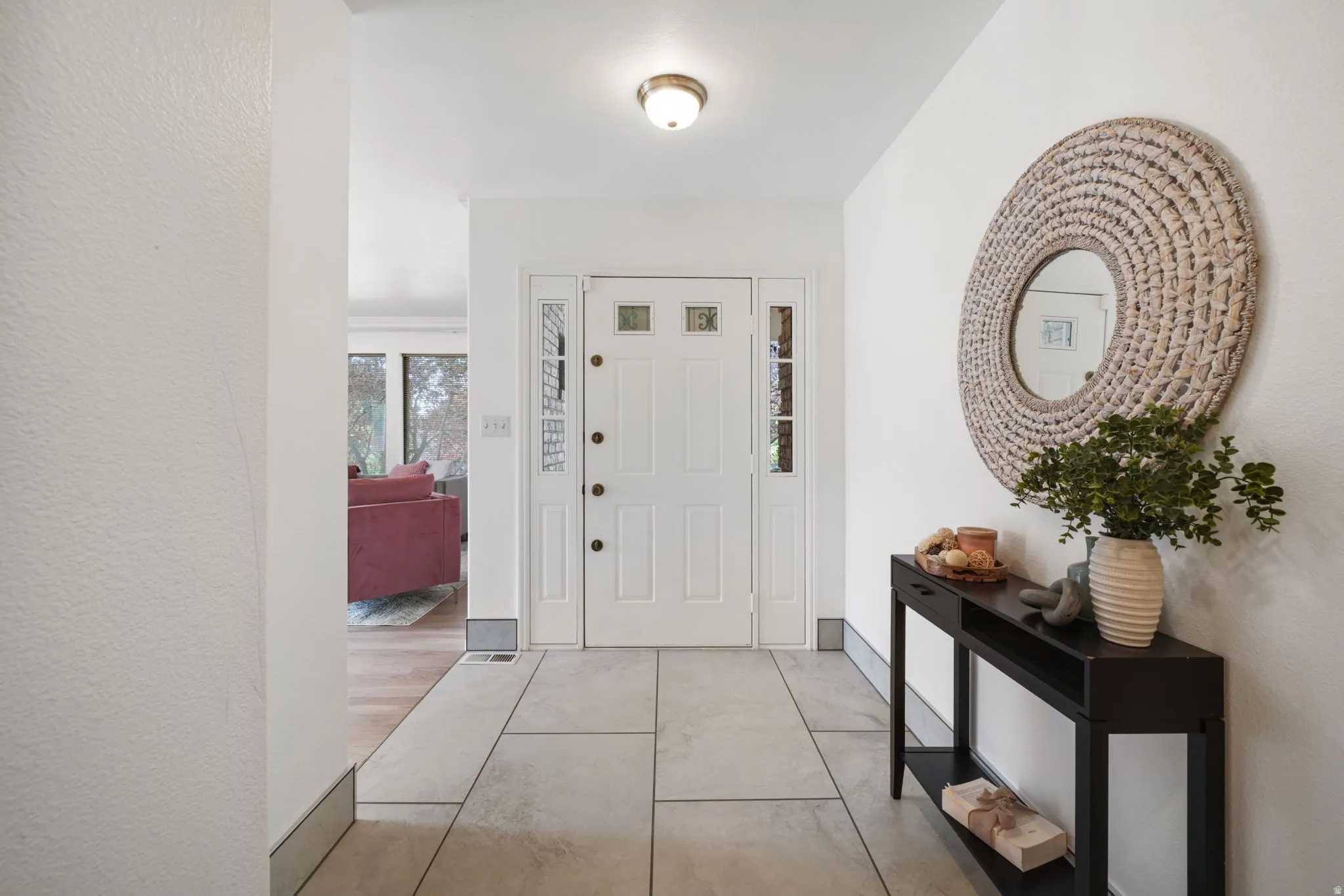 Entryway featuring large format tile flooring, a white paneled entry door with decorative glass inserts, and matching sidelight windows
