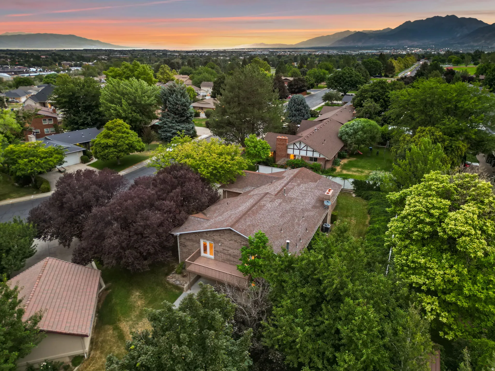 Residential property with a multi-level roofline, featuring a private deck and mature landscaping
