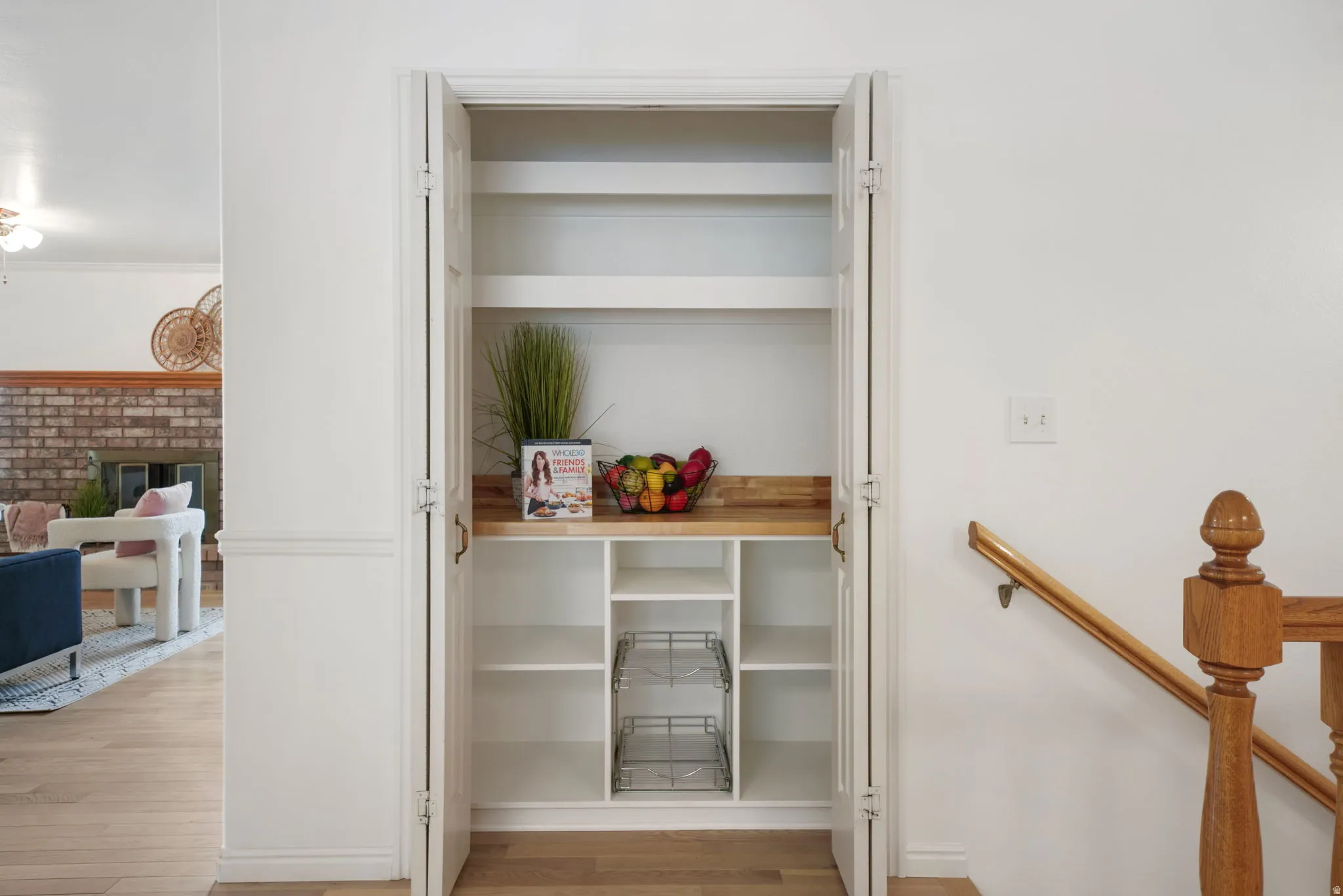Built-in pantry featuring white shelving, a wood-finish countertop, and bi-fold doors