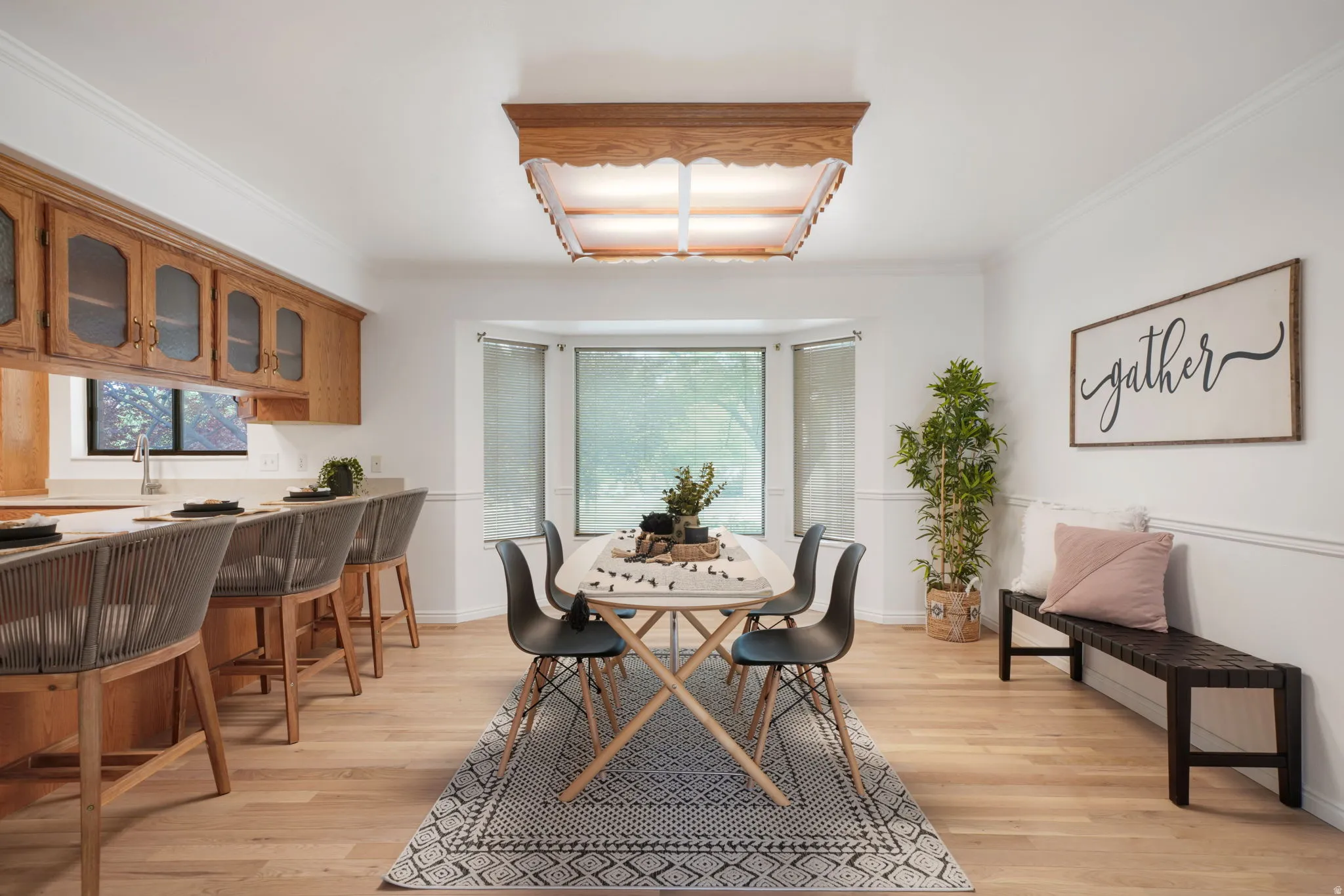 Open-concept dining area featuring wood-finish flooring, a bay window, and a built-in kitchen bar with seating
