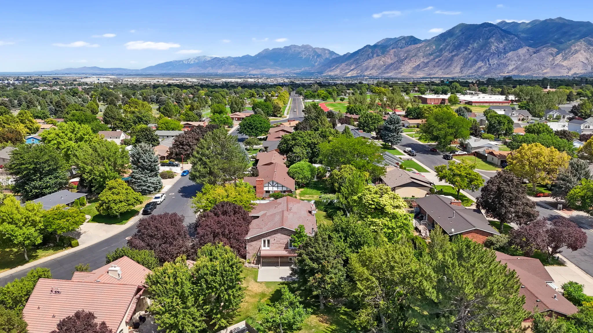 Mature treeline neighborhood with mountain backdrop, featuring paved roads and residential architecture