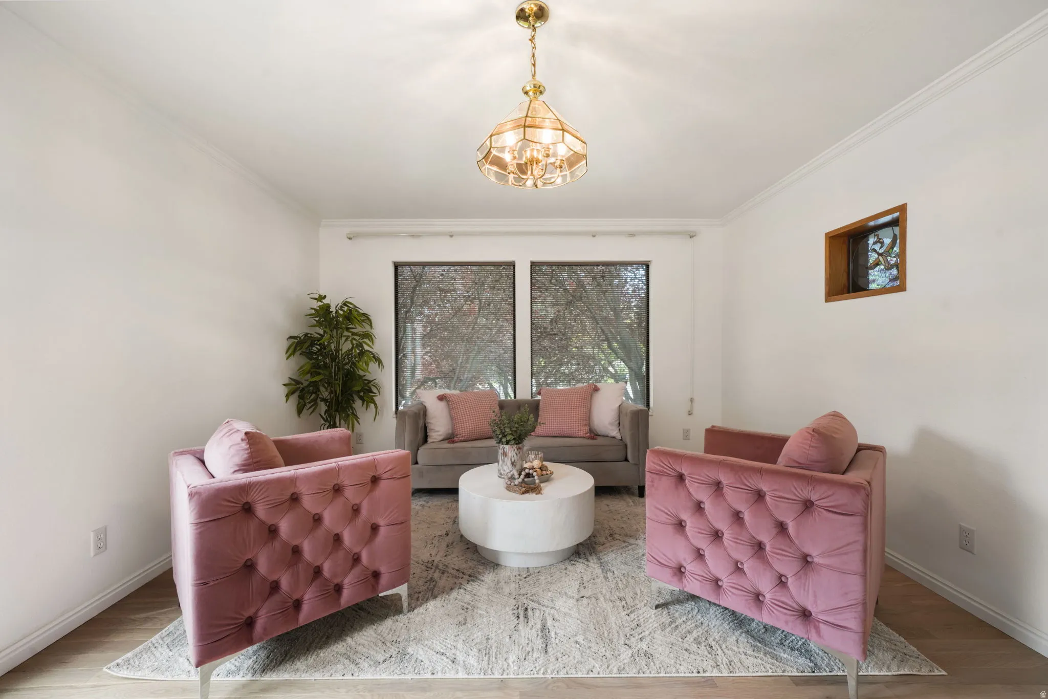 Bright interior room featuring wood-finish flooring, a contemporary ceiling light fixture, and crown molding