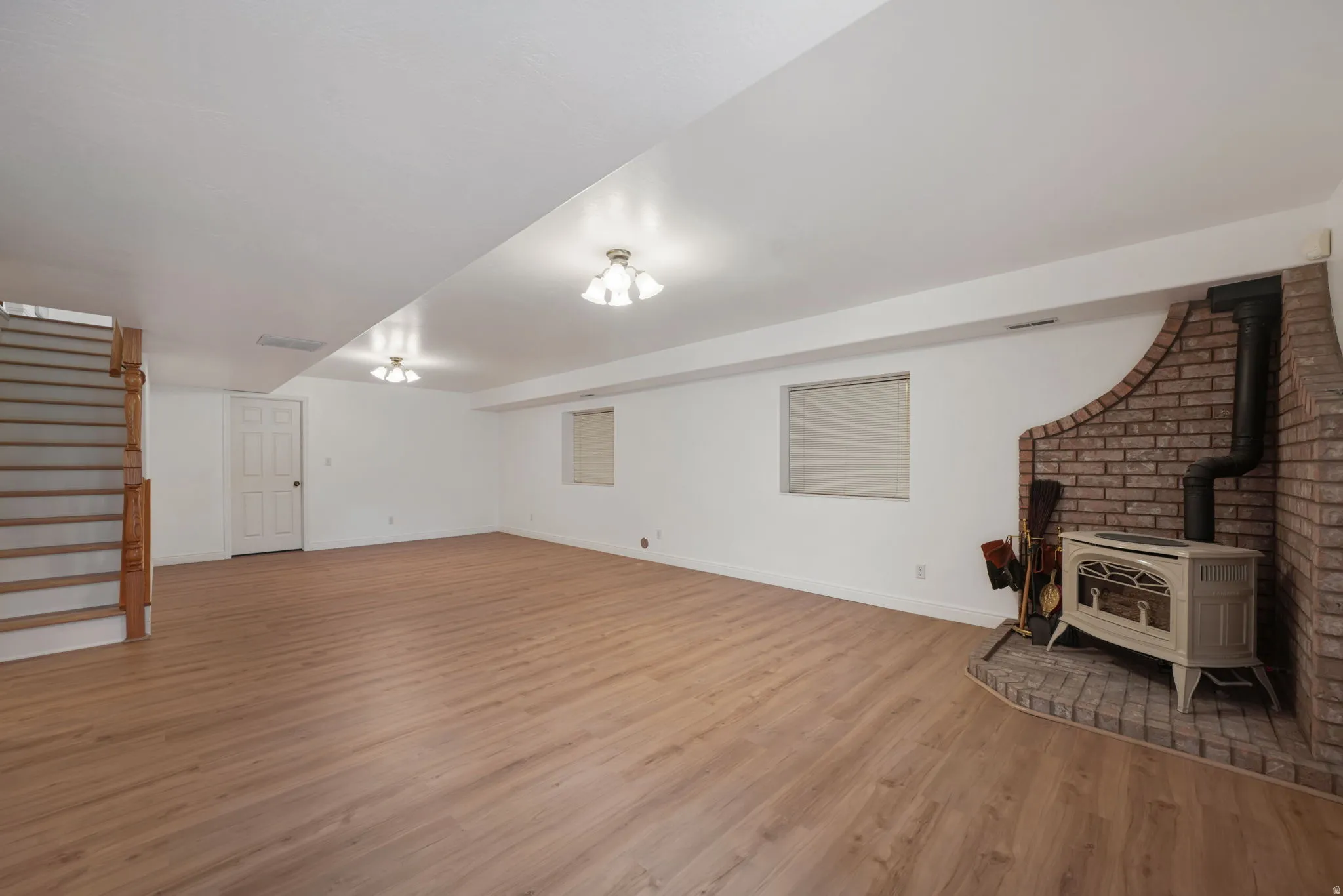 Spacious room featuring wood-finish flooring, white walls, and recessed lighting