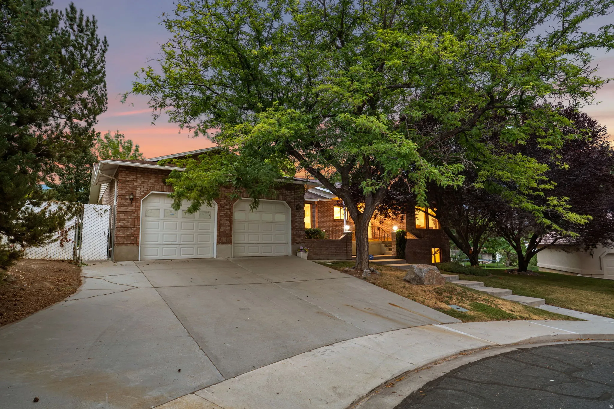Brick-clad residence featuring a two-car garage and a wide concrete driveway