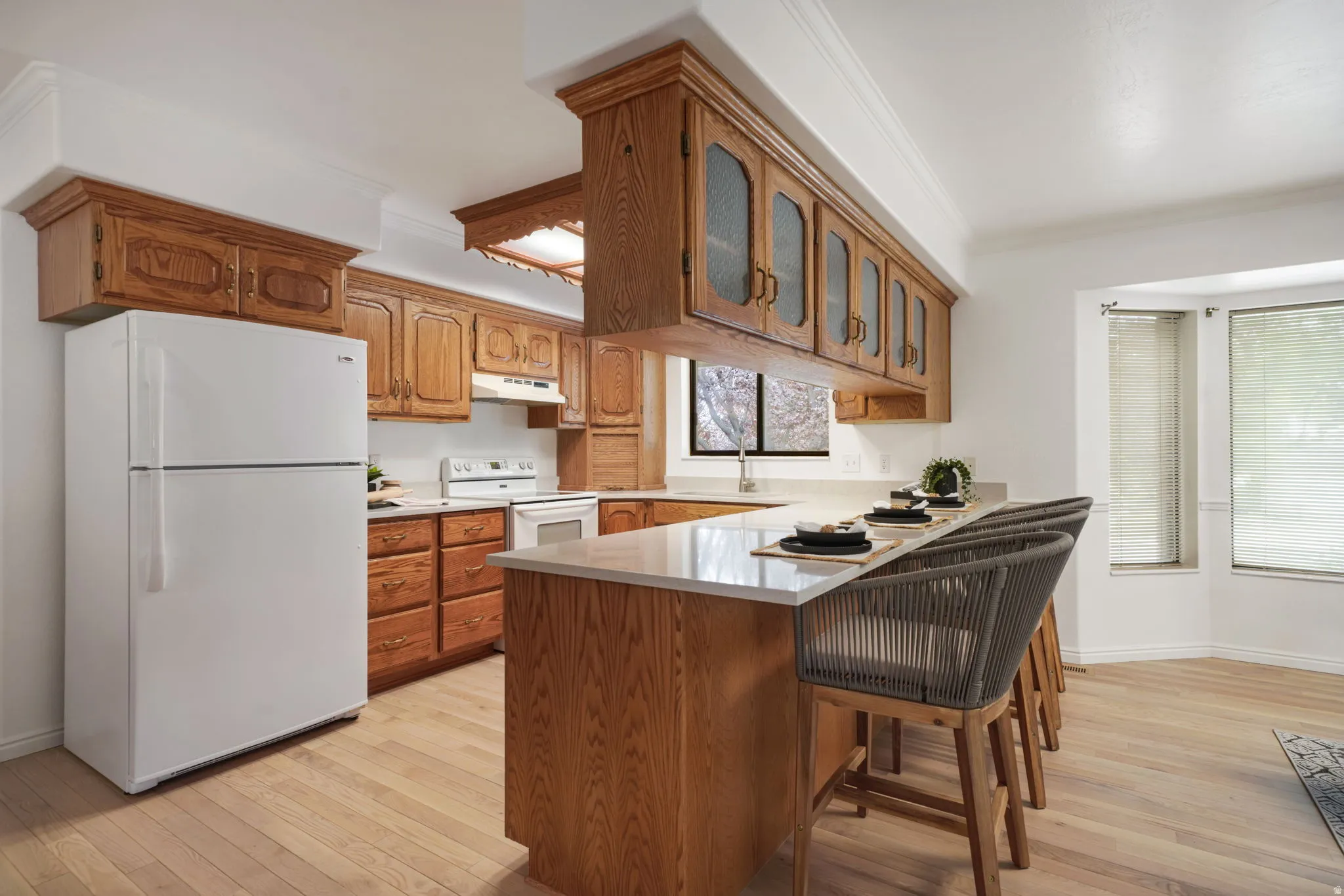 Light wood-finish flooring complements the wood cabinetry and light countertops in this kitchen