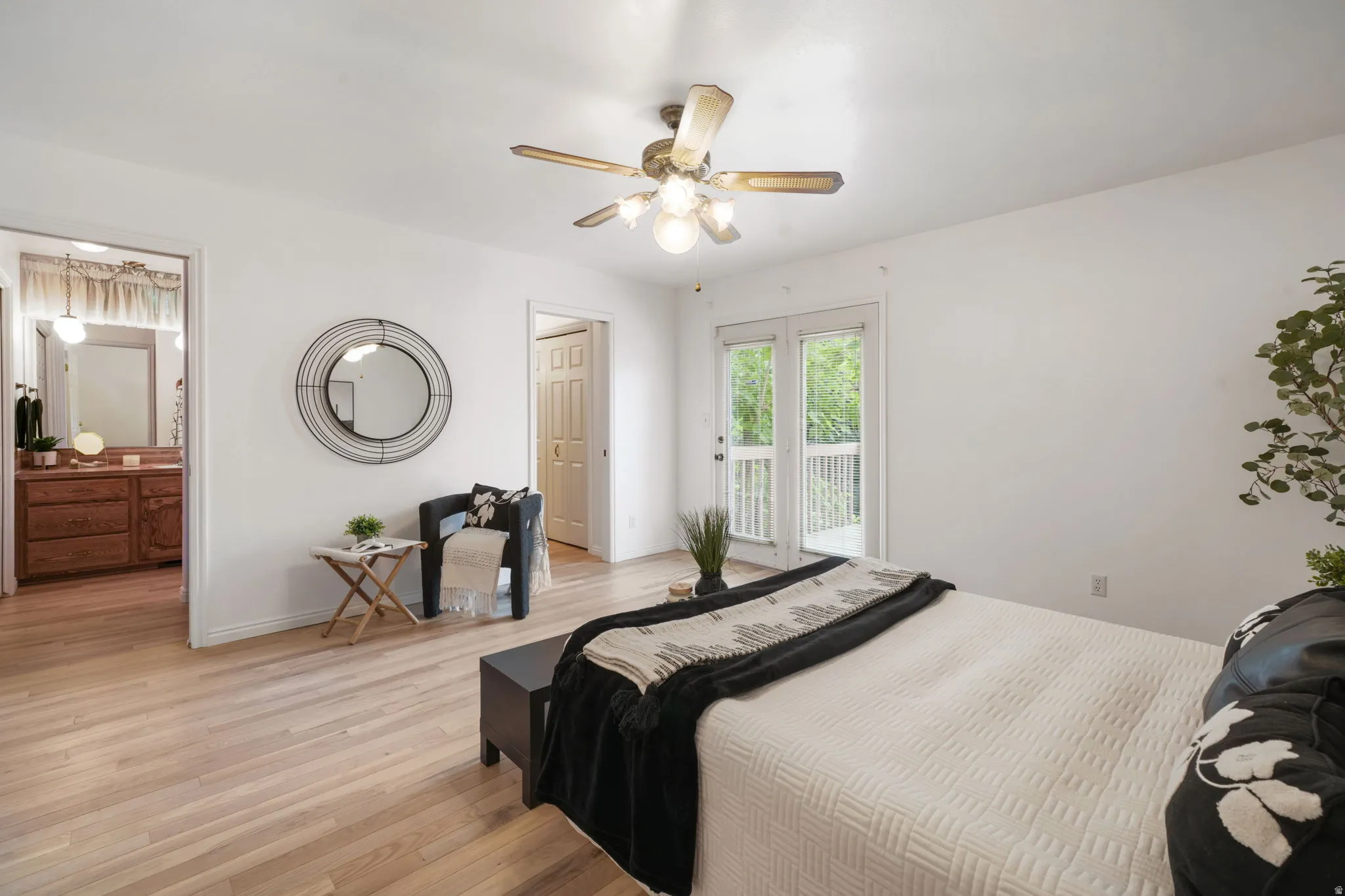 Light wood-finish flooring complements the bright white walls and ceiling fan