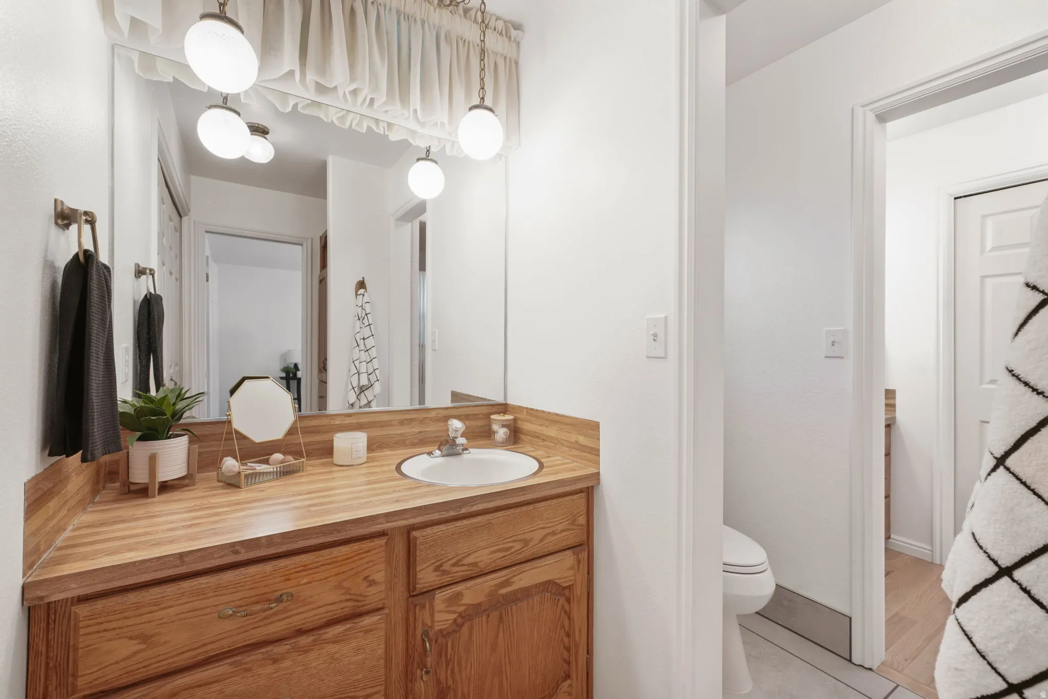 Wood-finish vanity with an integrated sink and base cabinetry, illuminated by two pendant light fixtures