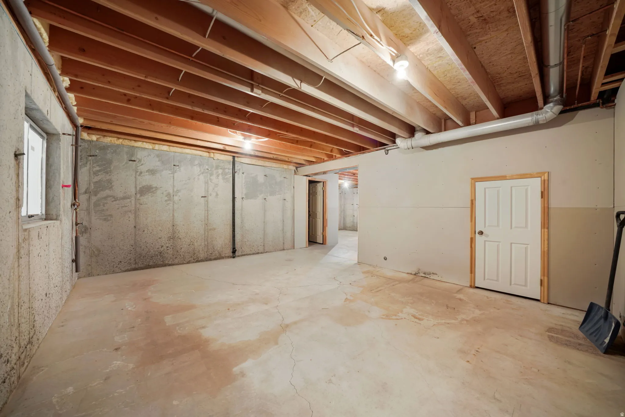 Unfinished basement with exposed wood joists and concrete flooring
