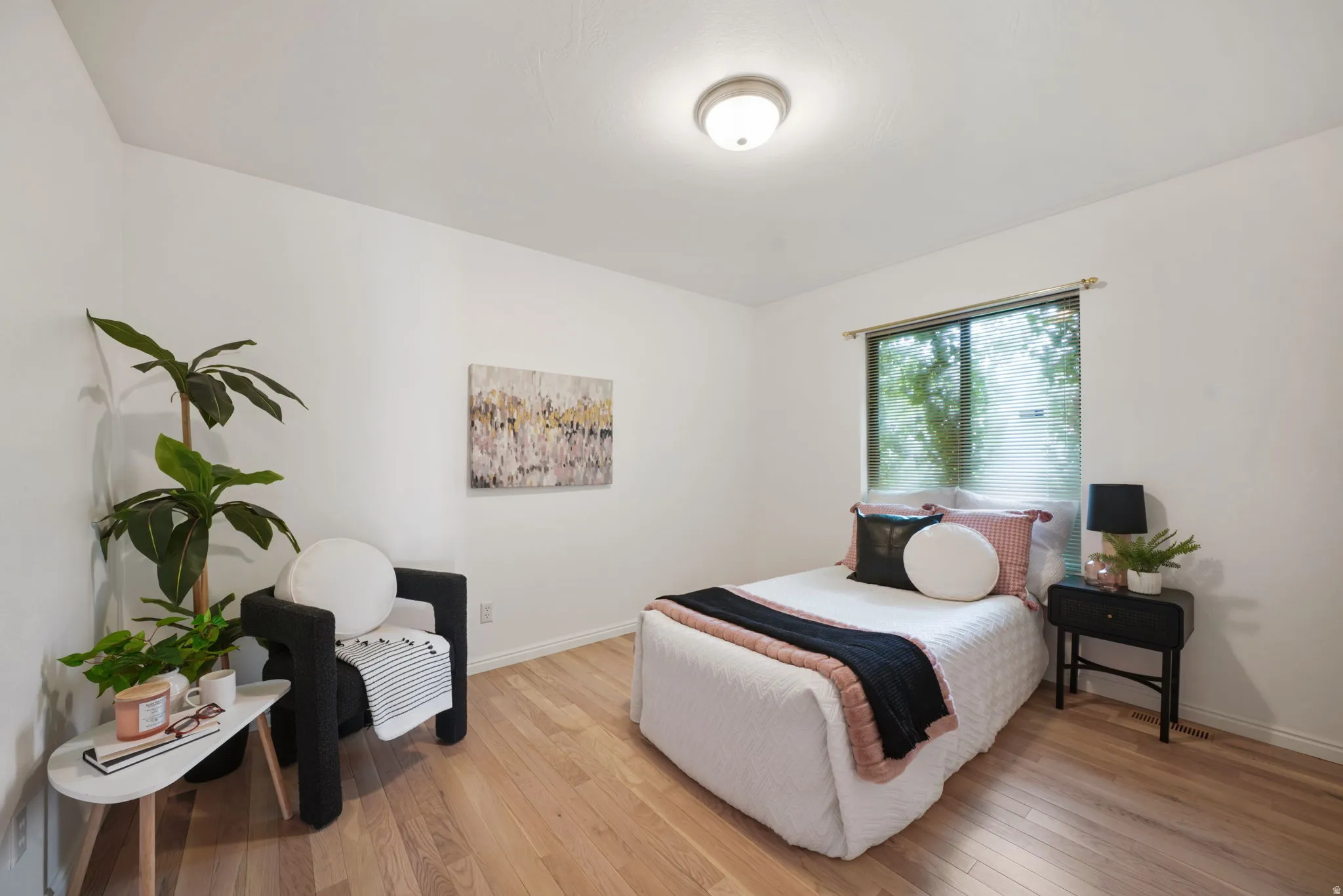 Bright interior room featuring wood-finish flooring, a window with exterior tree coverage, and a ceiling-mounted light fixture