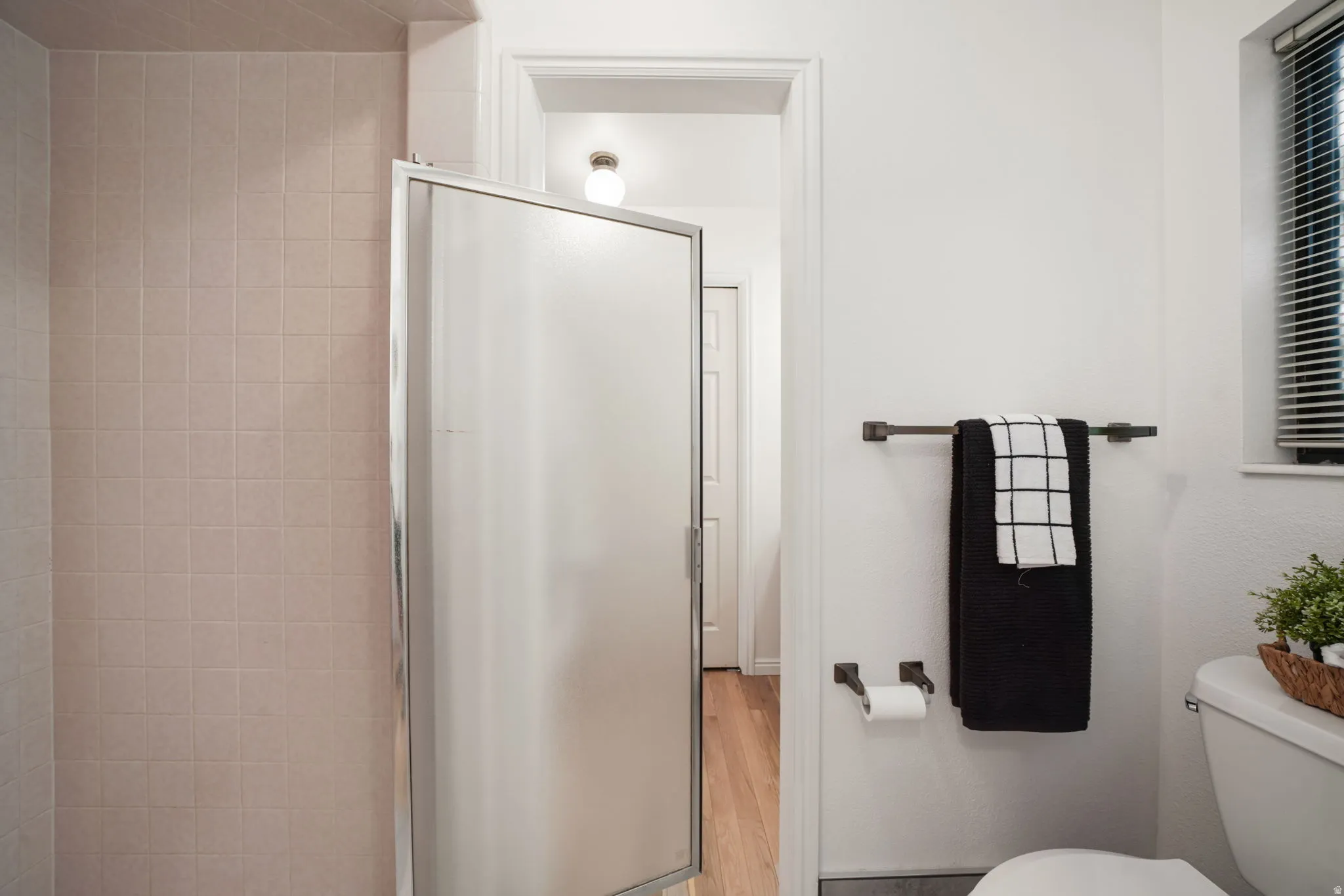 Shower enclosure with frosted glass door, light-toned square wall tiles, and white walls