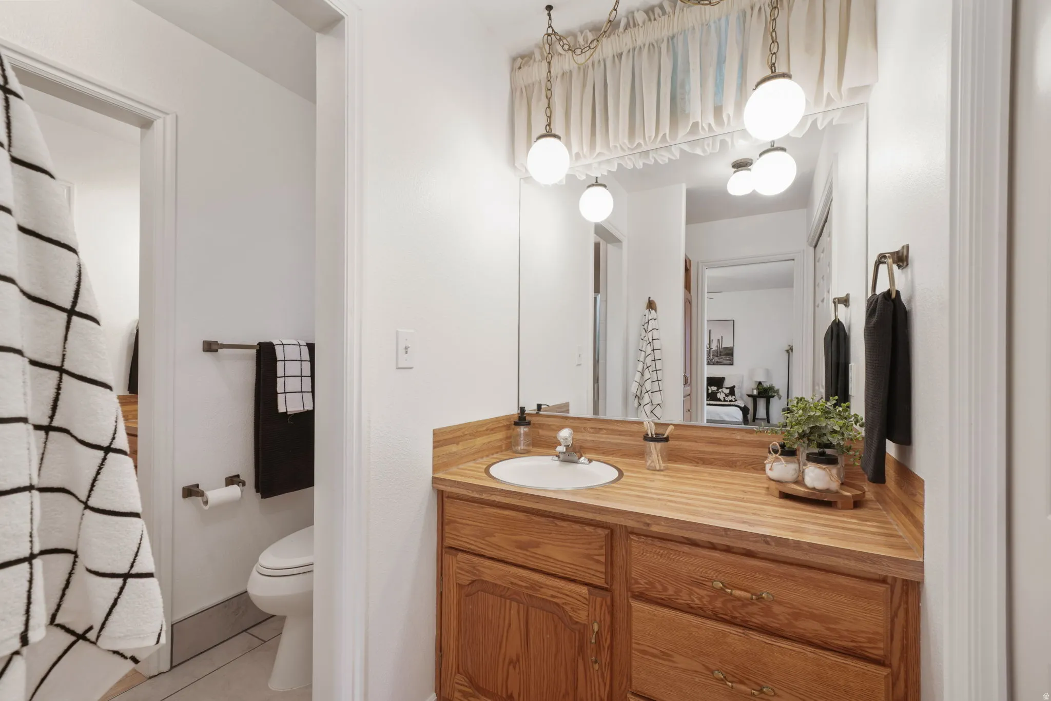 Bathroom featuring a wood-finish vanity with an integrated sink and brushed nickel faucet, a large mirror, and sconce lighting