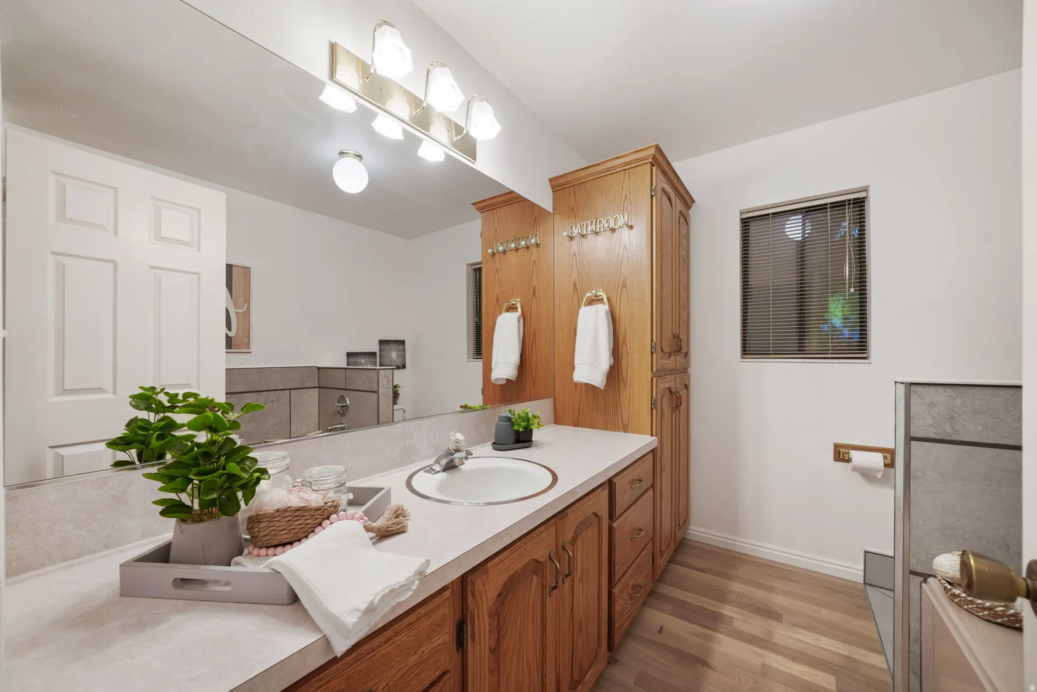 Full vanity with integrated sink, wood-finish cabinetry, and a full-width mirror
