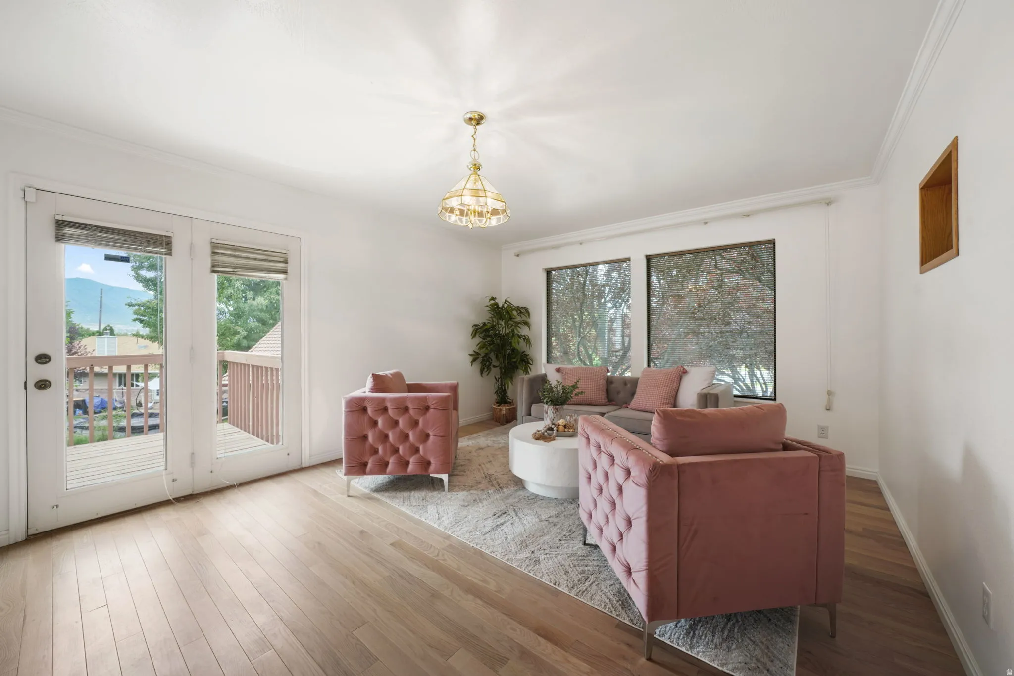 Spacious room featuring wood-finish flooring, white walls, and a decorative ceiling light fixture