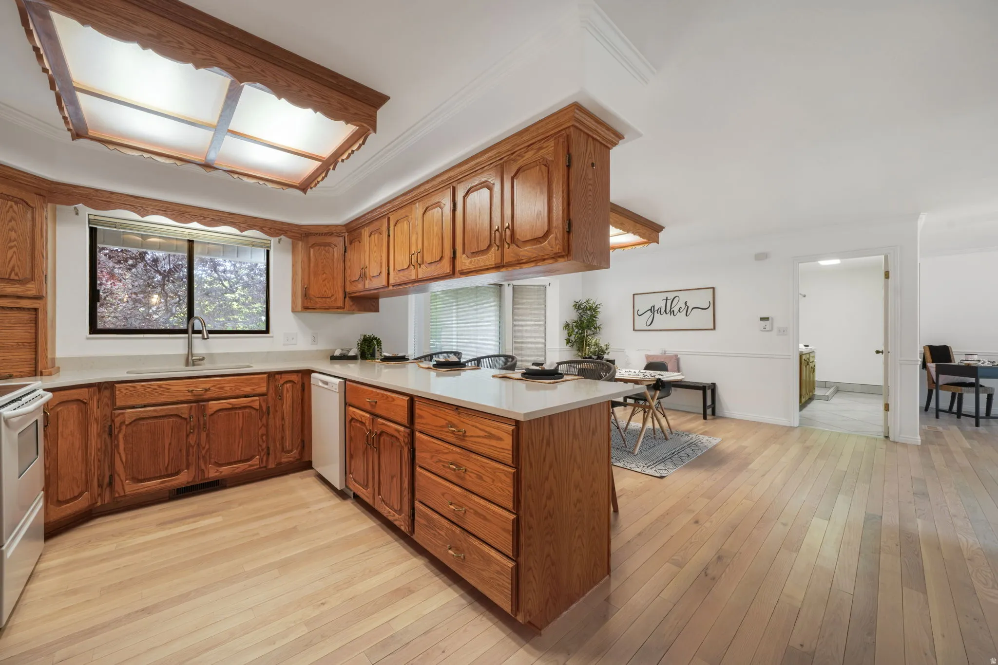 Open-concept kitchen featuring wood cabinetry, light-toned countertops, and wood-finish flooring