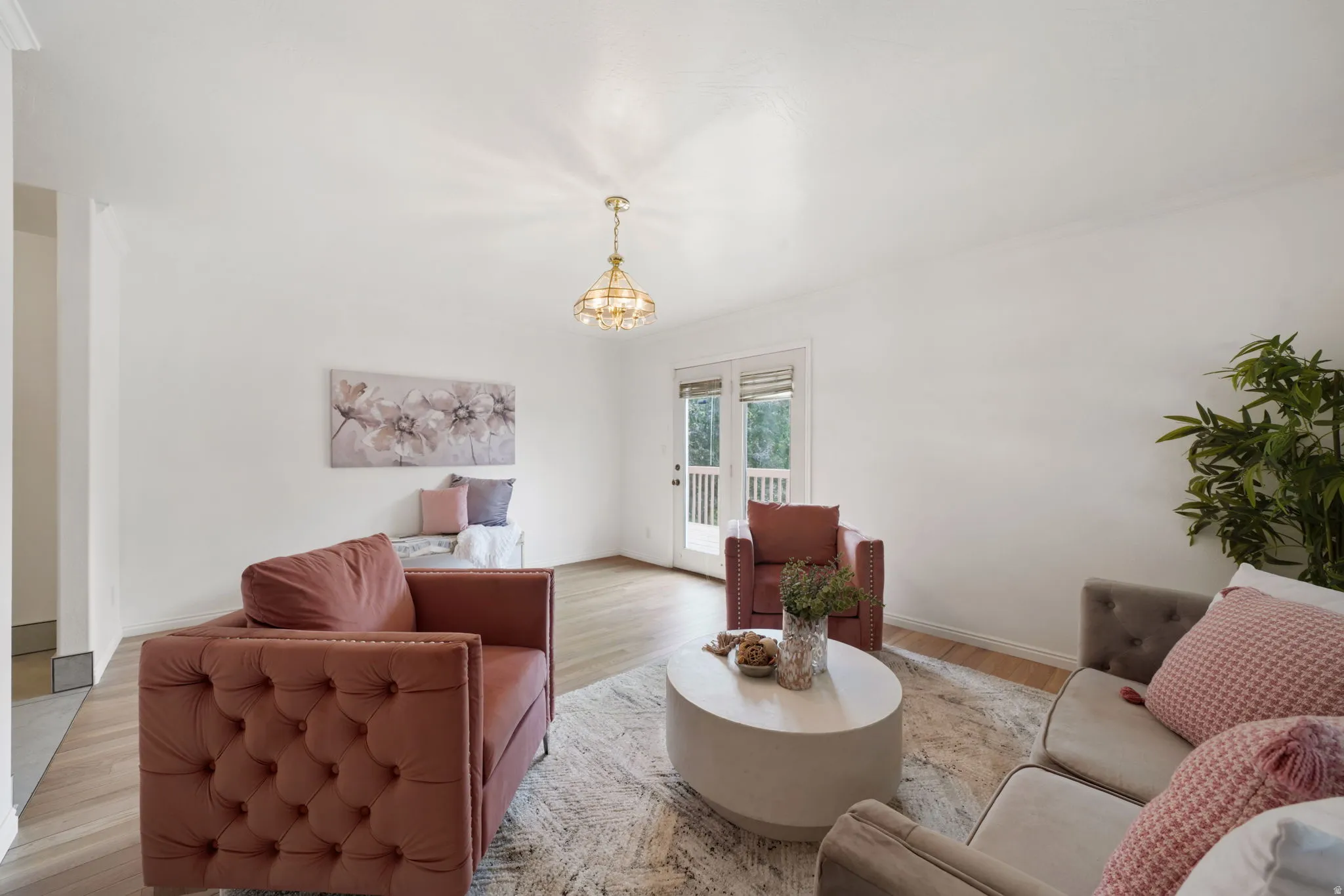 Living area featuring wood-finish flooring, a contemporary chandelier, and white walls