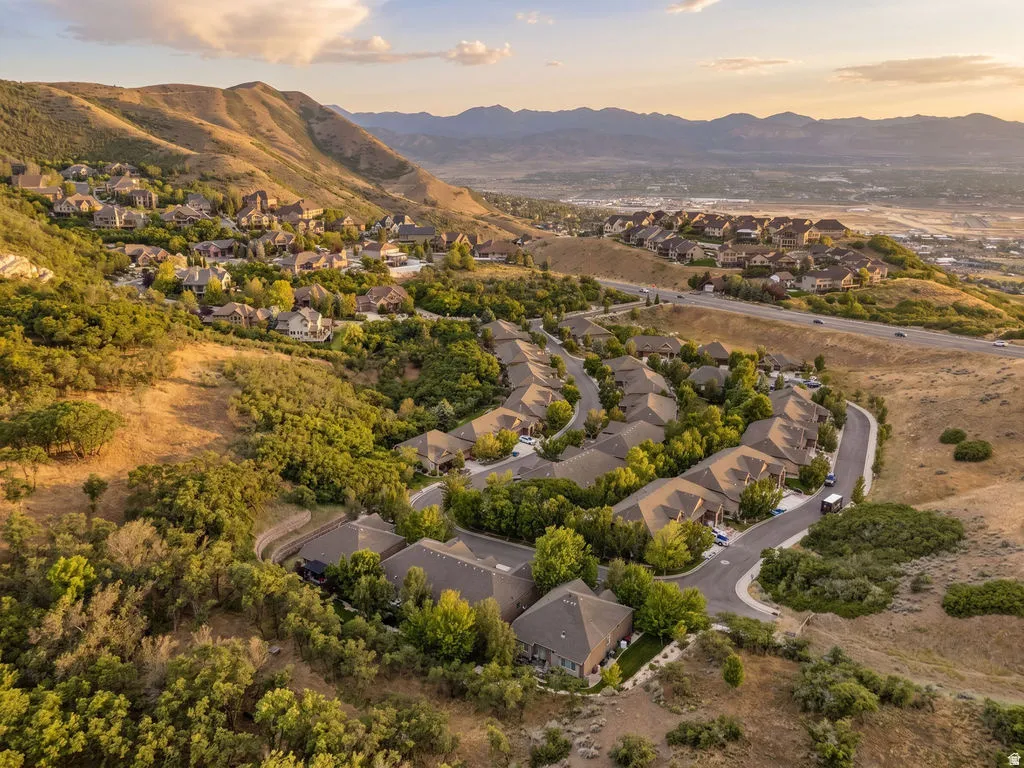 Hillside community featuring residential homes with sloped rooflines, surrounded by natural landscaping and mature trees