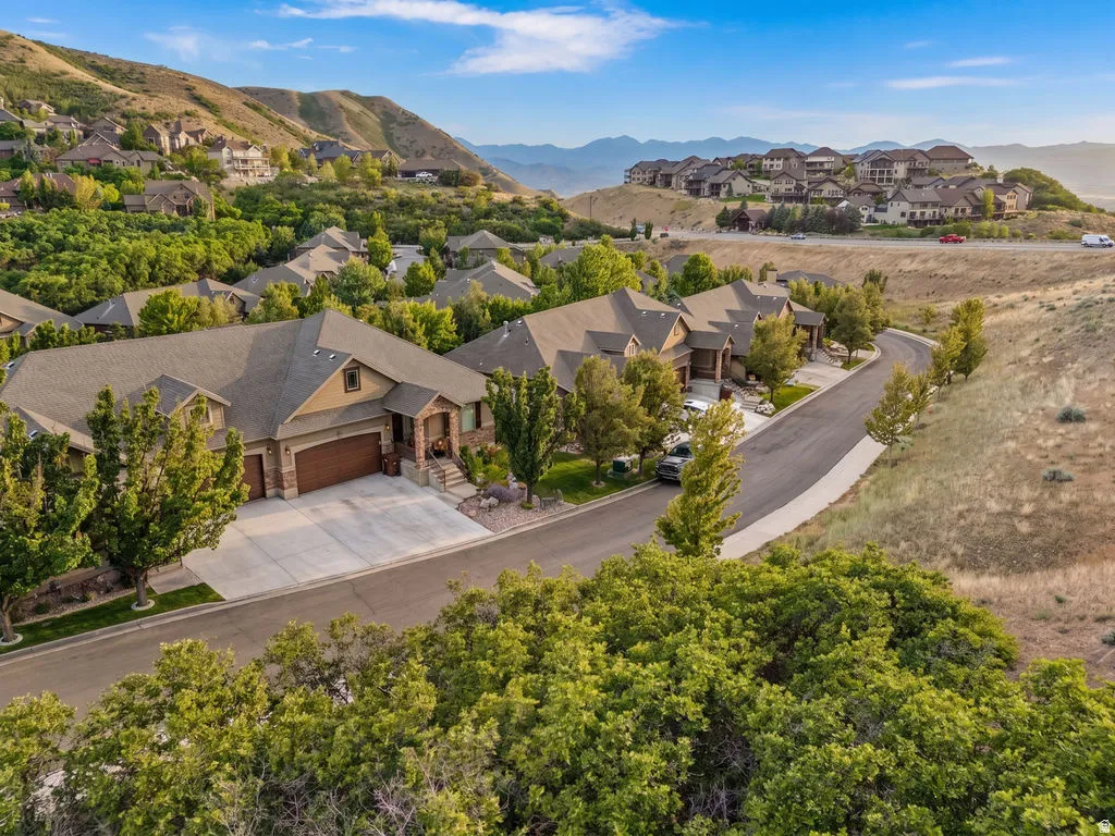 Contemporary residence featuring a multi-tone exterior, attached three-car garage, concrete driveway, and mature landscaping