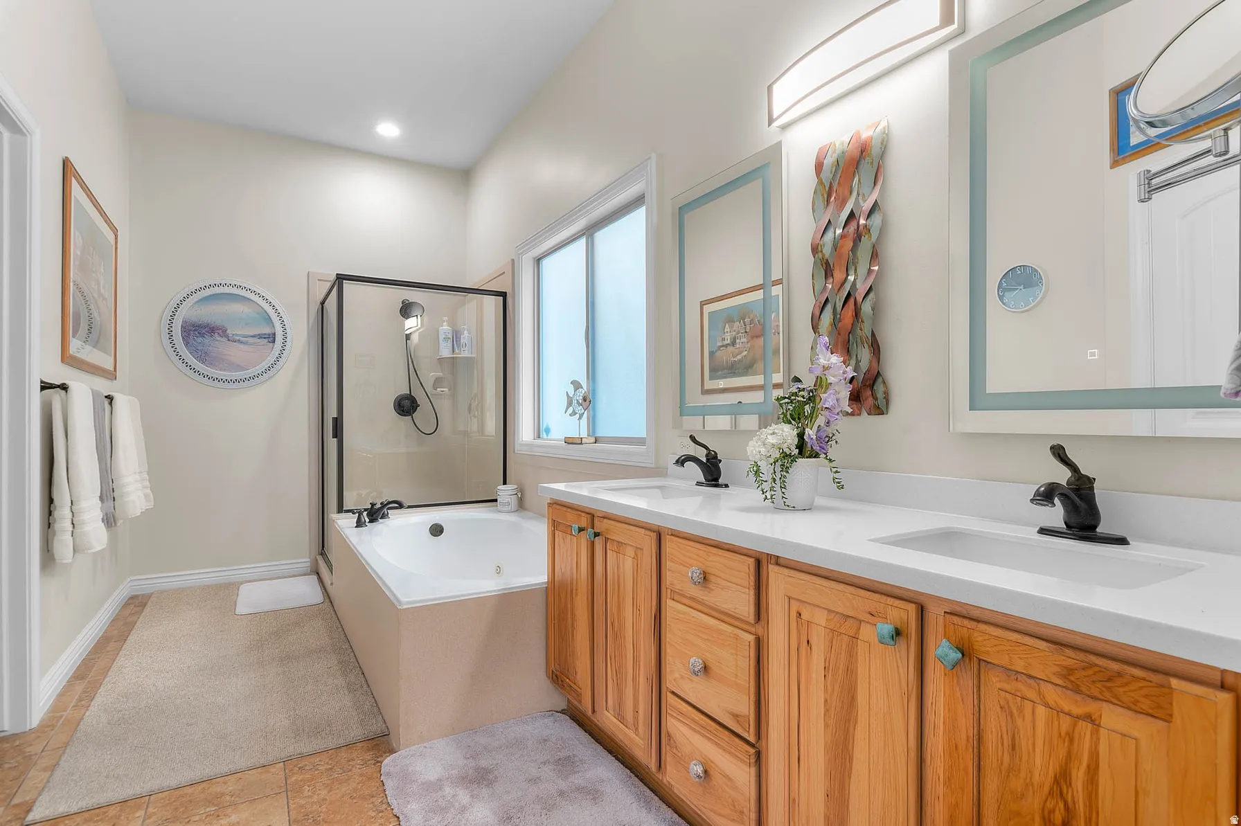 Spacious bathroom featuring a dual vanity with light wood cabinetry and white countertops
