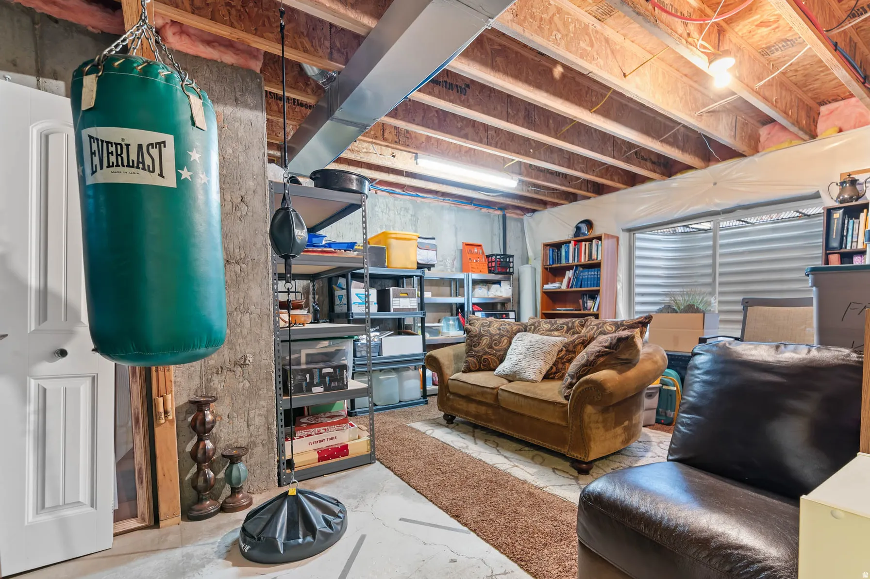 Unfinished basement space featuring exposed wood joists and concrete flooring
