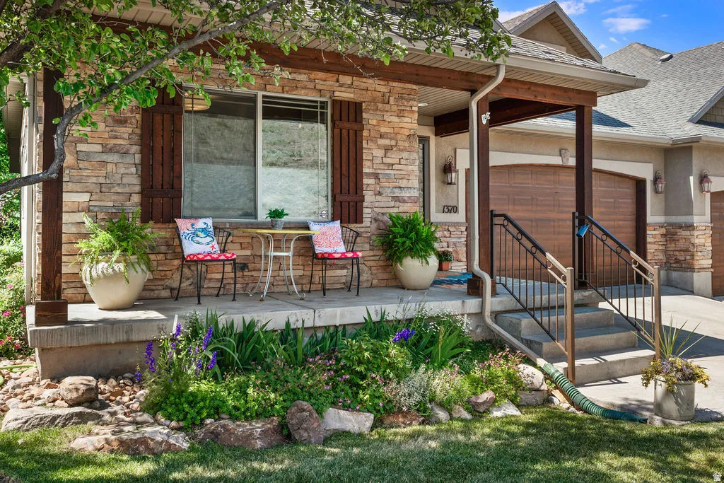 Stone facade exterior featuring dark wood shutters and a covered porch