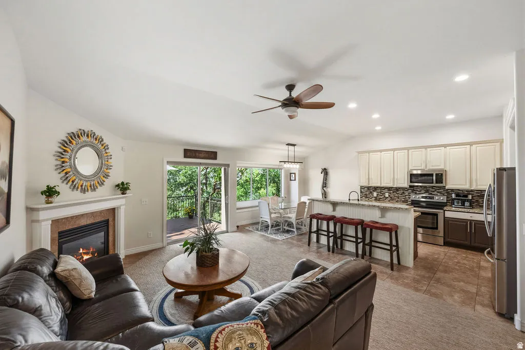 Spacious living area featuring a fireplace with a mantel, vaulted ceilings, and carpet flooring