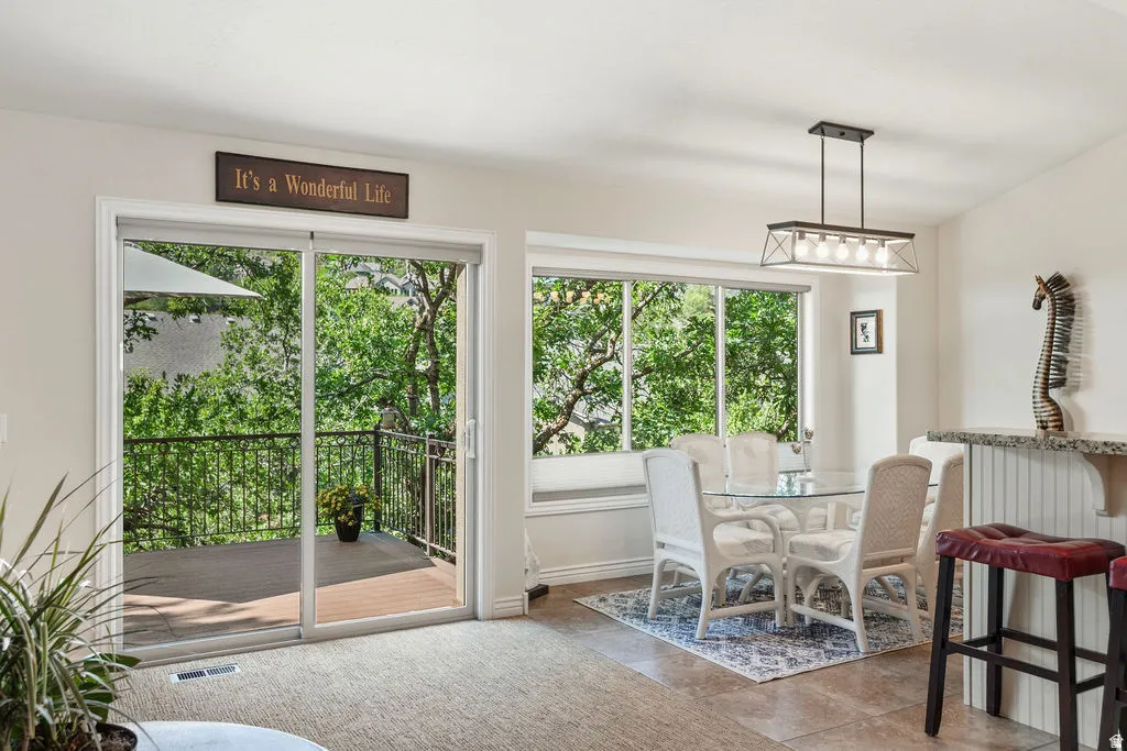 Dining area featuring a modern linear pendant light fixture and a breakfast bar with a granite-look countertop