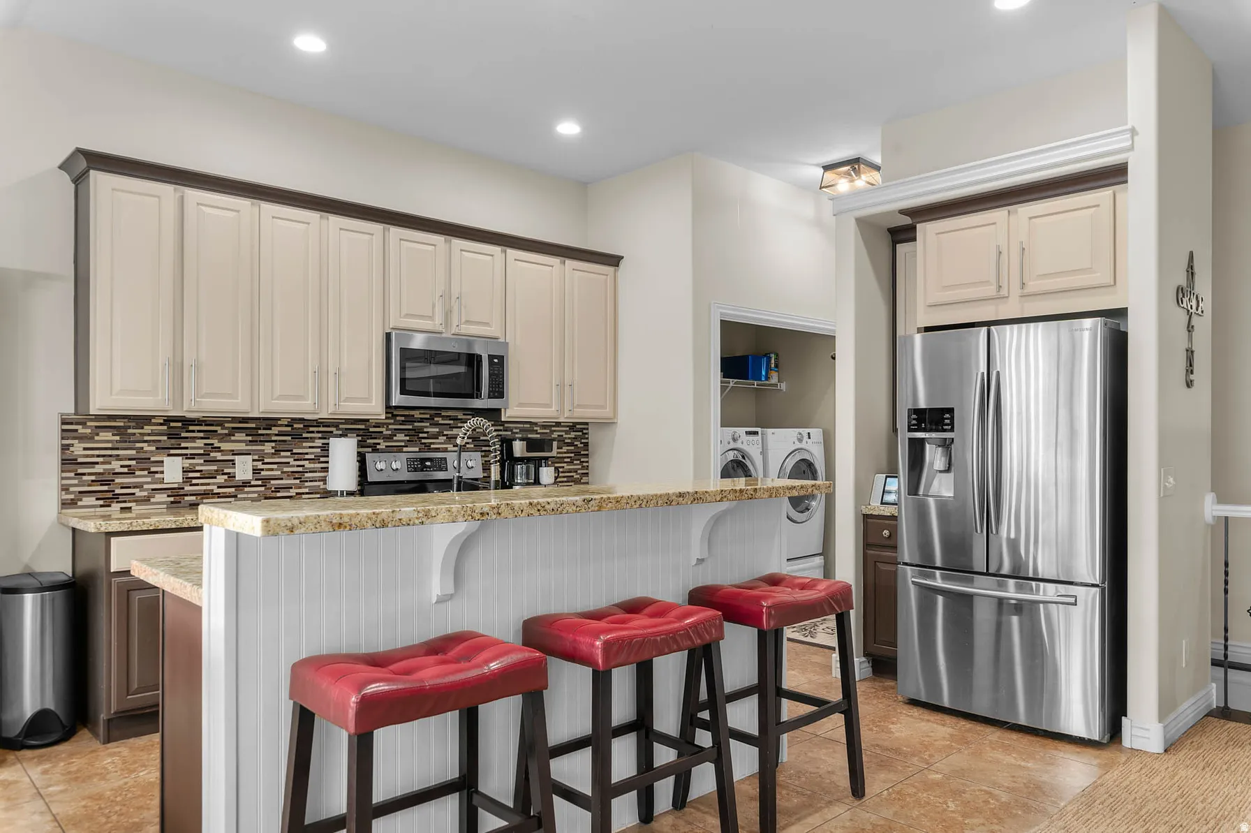 Kitchen featuring a breakfast bar with beadboard paneling, stainless steel appliances, recessed lighting, and a mosaic tile backsplash