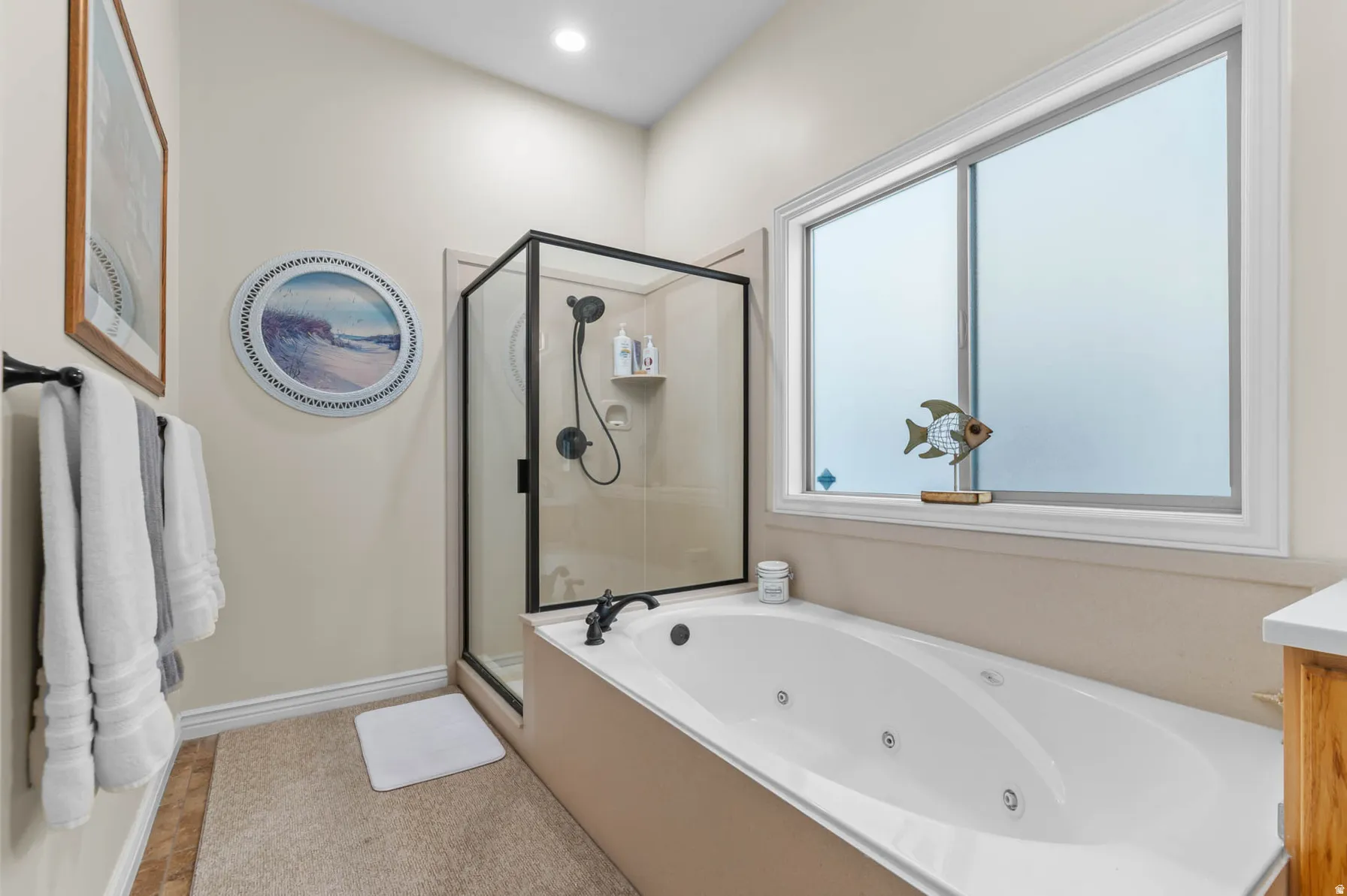 Enclosed shower with black-framed glass alongside a jetted soaking tub