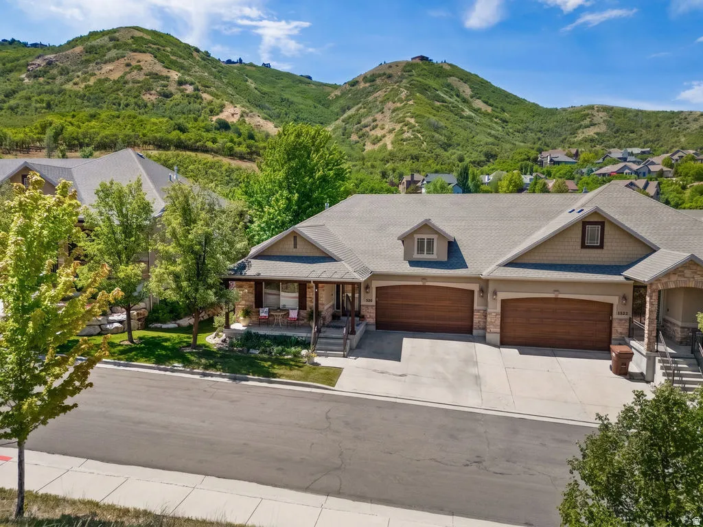 Ranch-style residence featuring a stone and siding exterior, a covered front porch, and a two-car garage with wood-finish doors