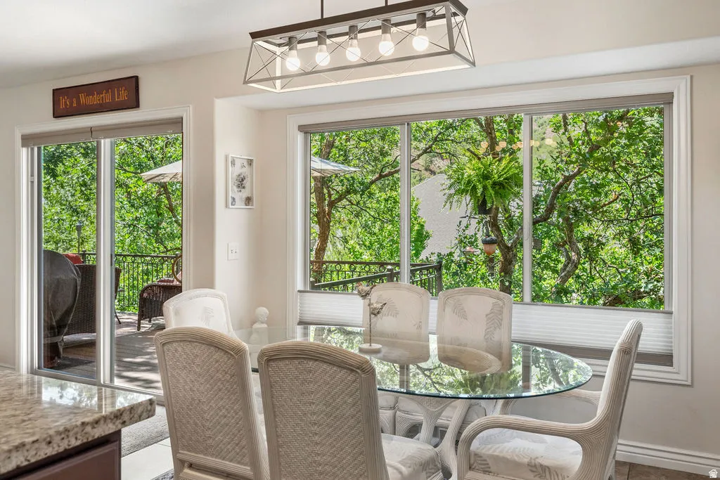 Dining area with abundant natural light, featuring a large picture window, sliding glass door access to an outdoor deck, and a contemporary linear light fixture