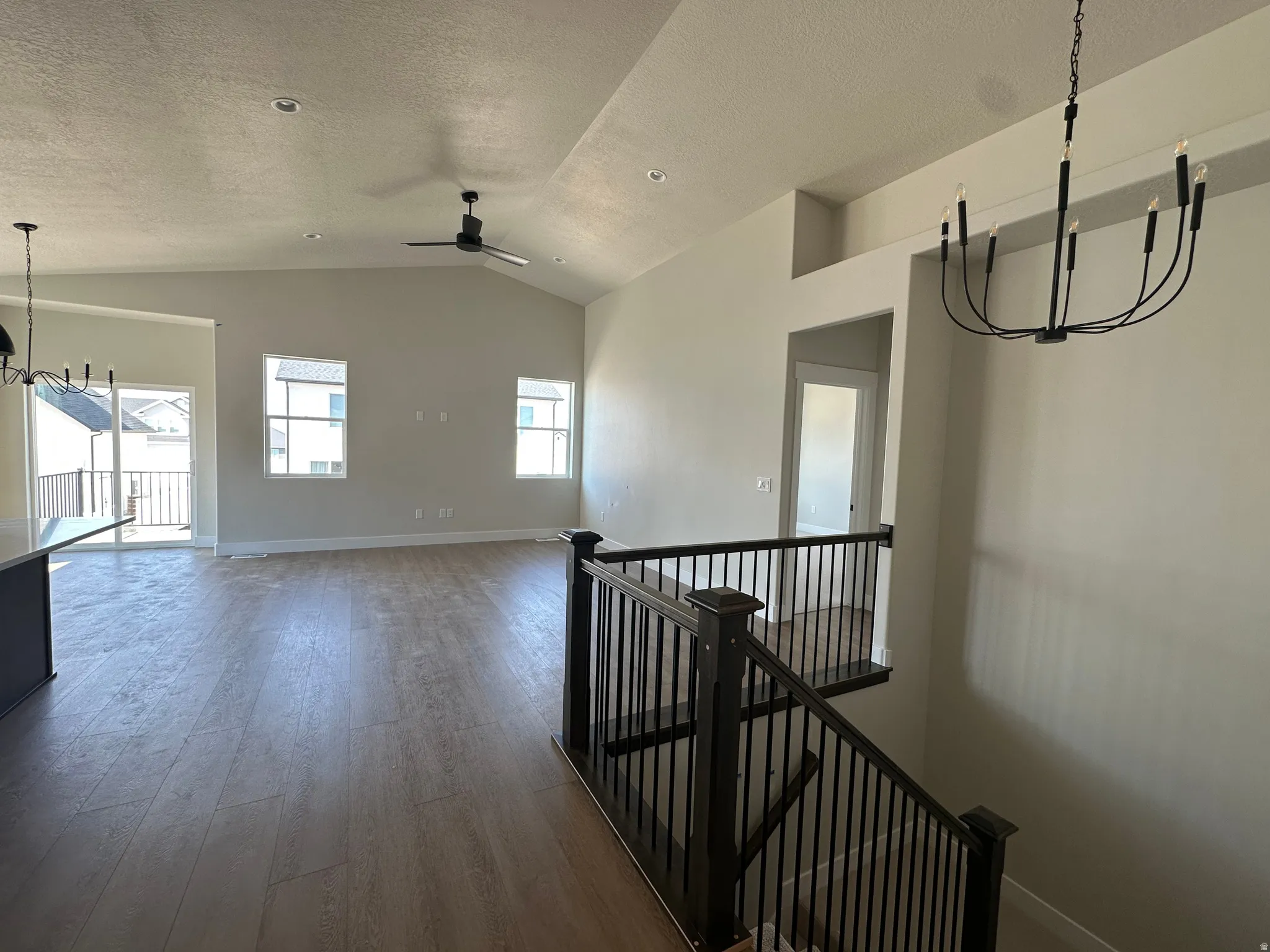 Vaulted ceilings, wood-finish flooring, two windows, recessed lighting, and a contemporary chandelier