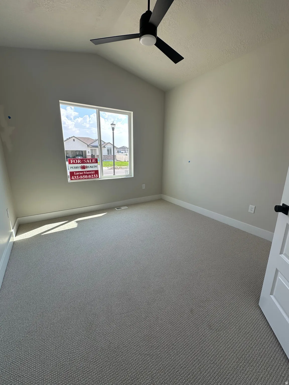 Vaulted ceiling with a black ceiling fan, neutral carpet flooring, and a white interior door with dark hardware