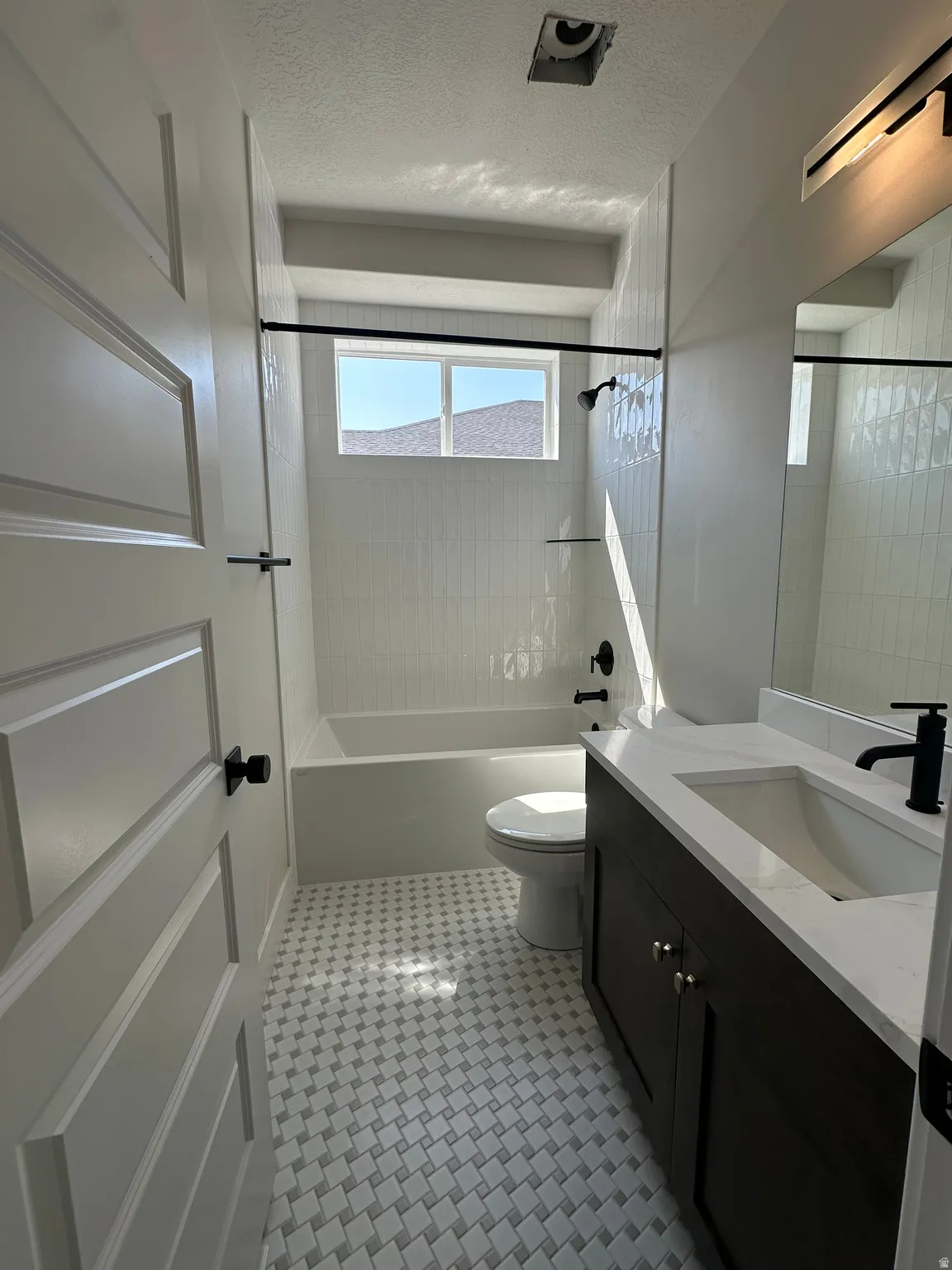 Bathroom featuring a dark wood-finish vanity, integrated sink, and patterned floor tiling