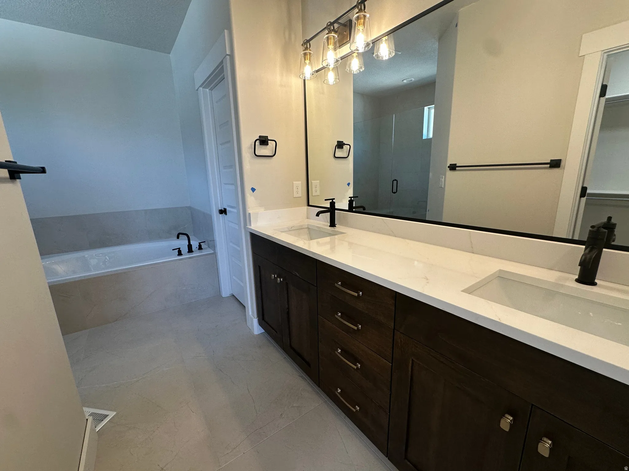 Dual vanity with white countertops, dark wood cabinetry, and rectangular undermount sinks