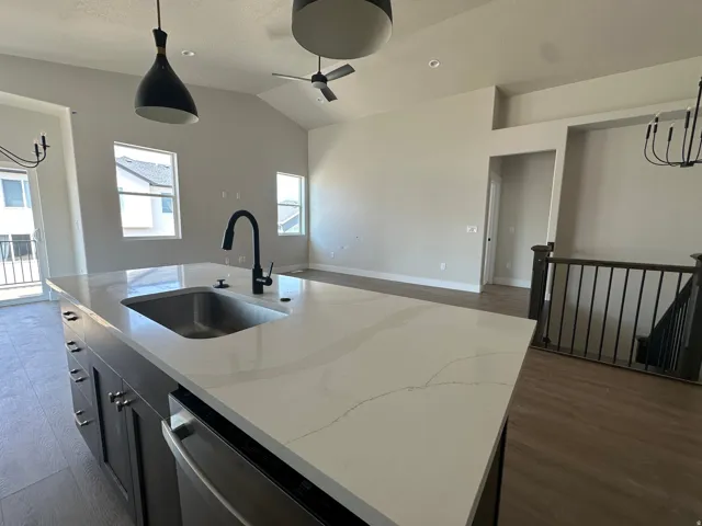 Kitchen island with a stainless steel sink, matte black faucet, and light-toned countertop