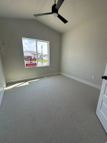 Vaulted ceiling with a black ceiling fan, neutral carpet flooring, and a white interior door with dark hardware