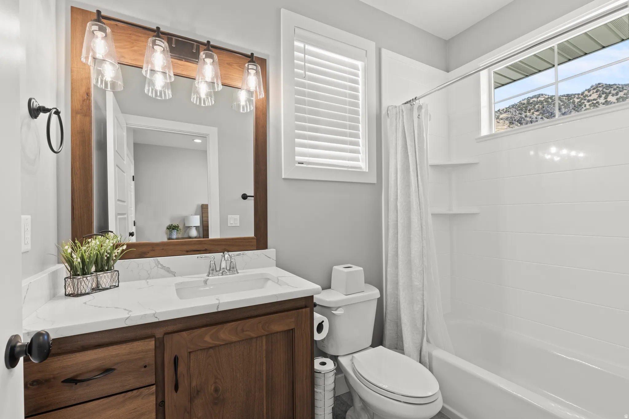 Bathroom featuring a wood-finish vanity with a quartz-finish countertop and an undermount sink