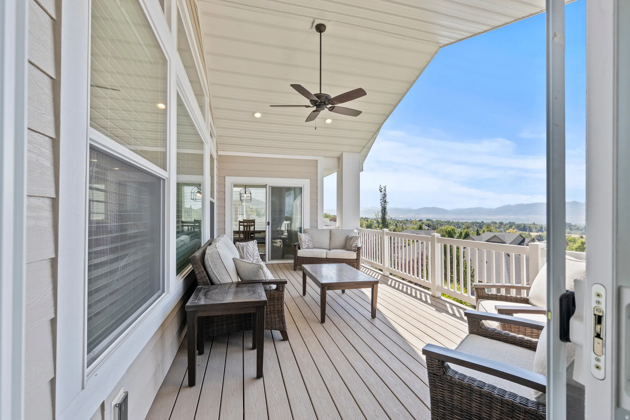 Spacious covered deck featuring composite decking, white railing, and a ceiling fan