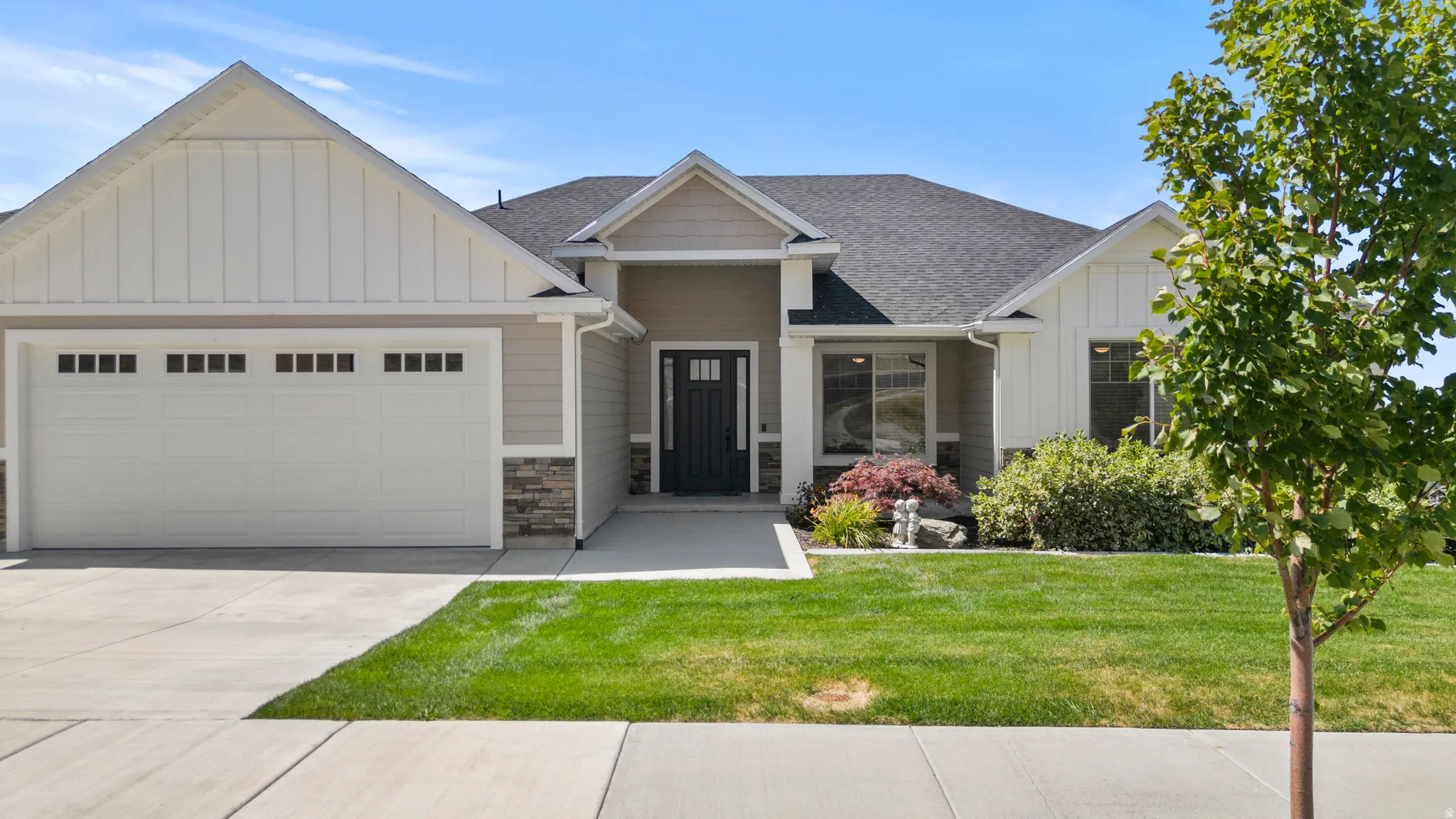 Contemporary single-story residence featuring a dark asphalt shingle roof and a light gray siding exterior with white vertical board and batten accents