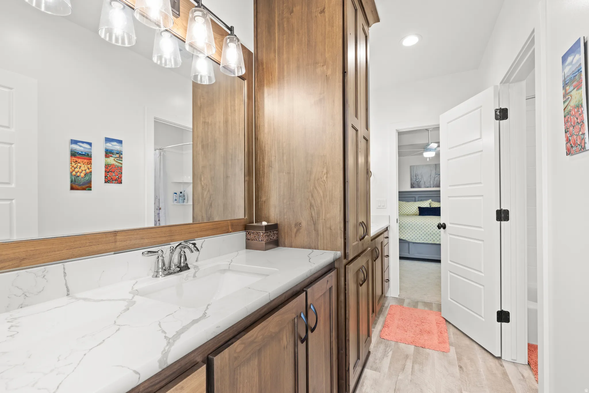 Bathroom vanity featuring a single sink, chrome faucet, and a large mirror with integrated lighting