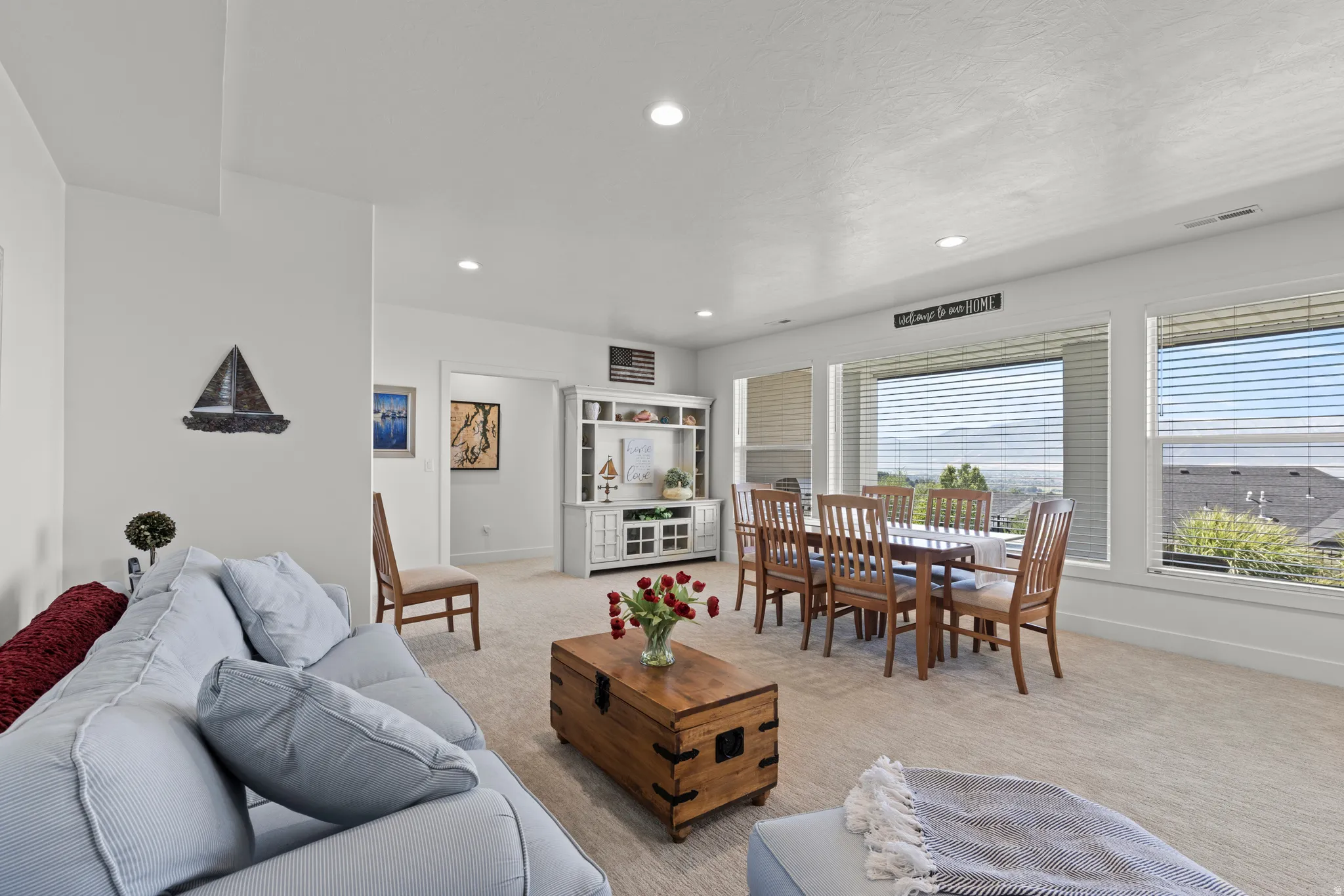 Open concept living space featuring recessed lighting, large windows with blinds, and light-toned carpeting