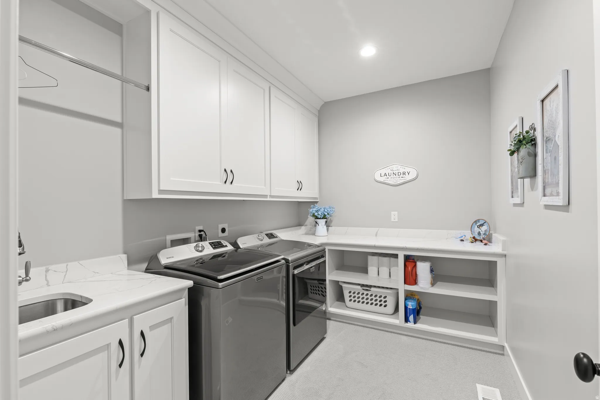 Laundry room featuring white cabinetry, a utility sink with a stone-finish countertop, open shelving, and a built-in hanging rod