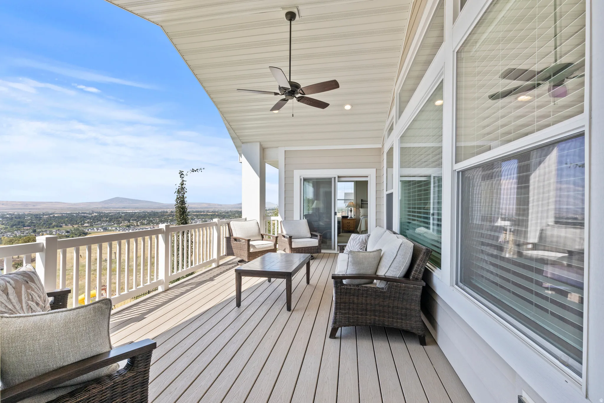 Expansive outdoor deck featuring composite decking, white railing, and a covered ceiling with a ceiling fan