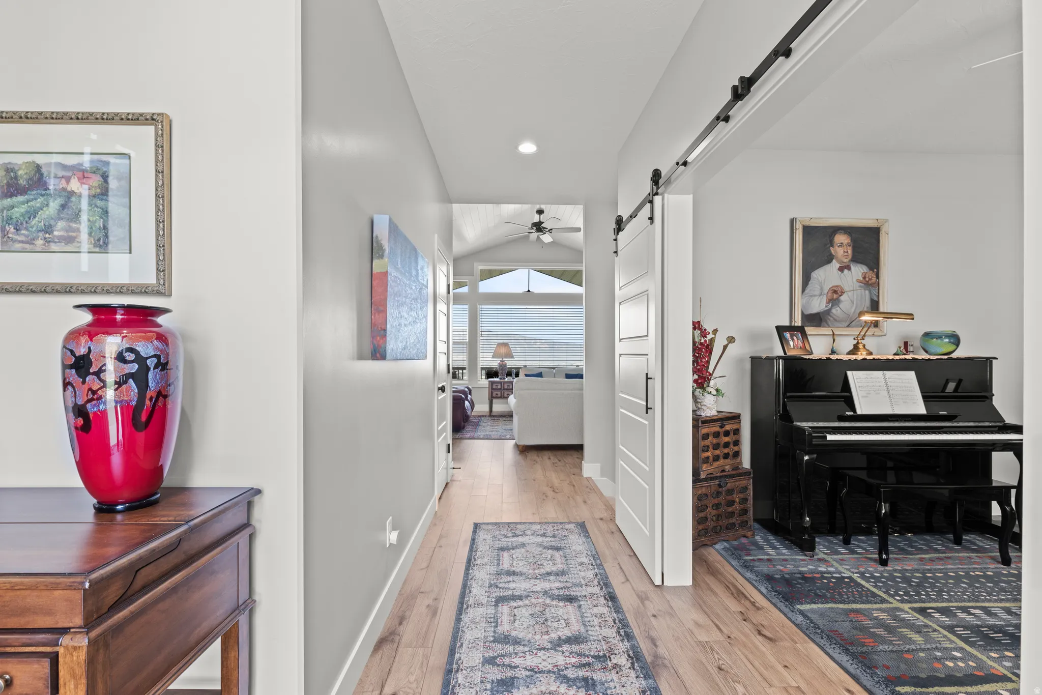 Hallway featuring wood-finish flooring, a modern barn door on a black track, and recessed lighting