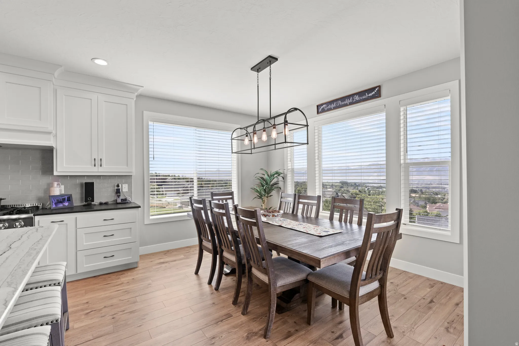 Dining area with wood-finish flooring and ample natural light from multiple windows