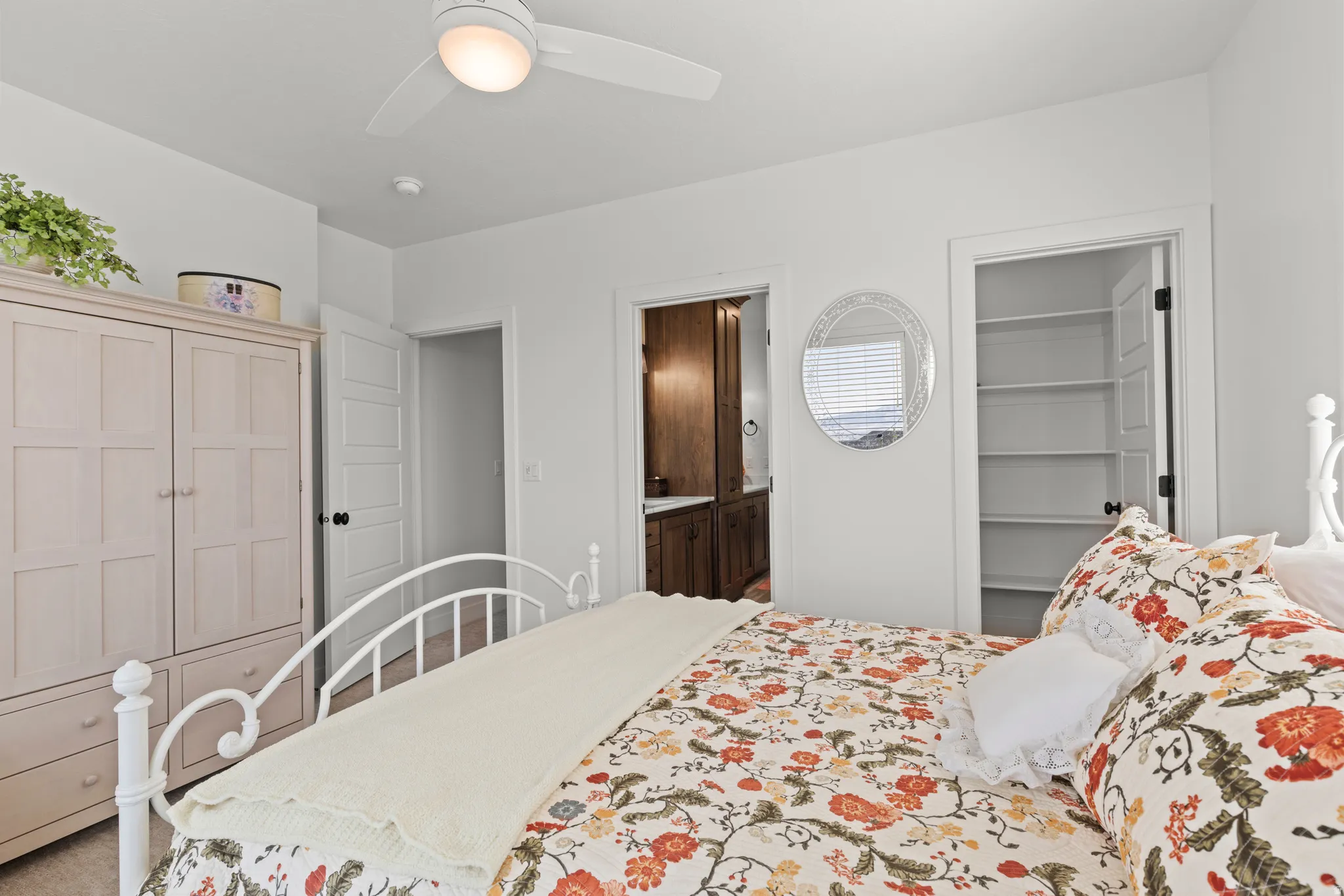 Bright interior featuring a ceiling fan with integrated lighting, a built-in closet with shelving, and a partially visible bathroom with wood-finish cabinetry