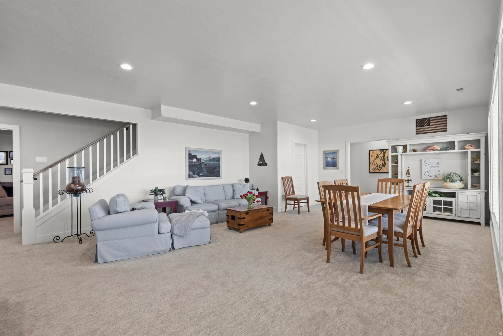 Spacious open-concept area featuring recessed lighting, light-toned carpeting, and a built-in storage unit
