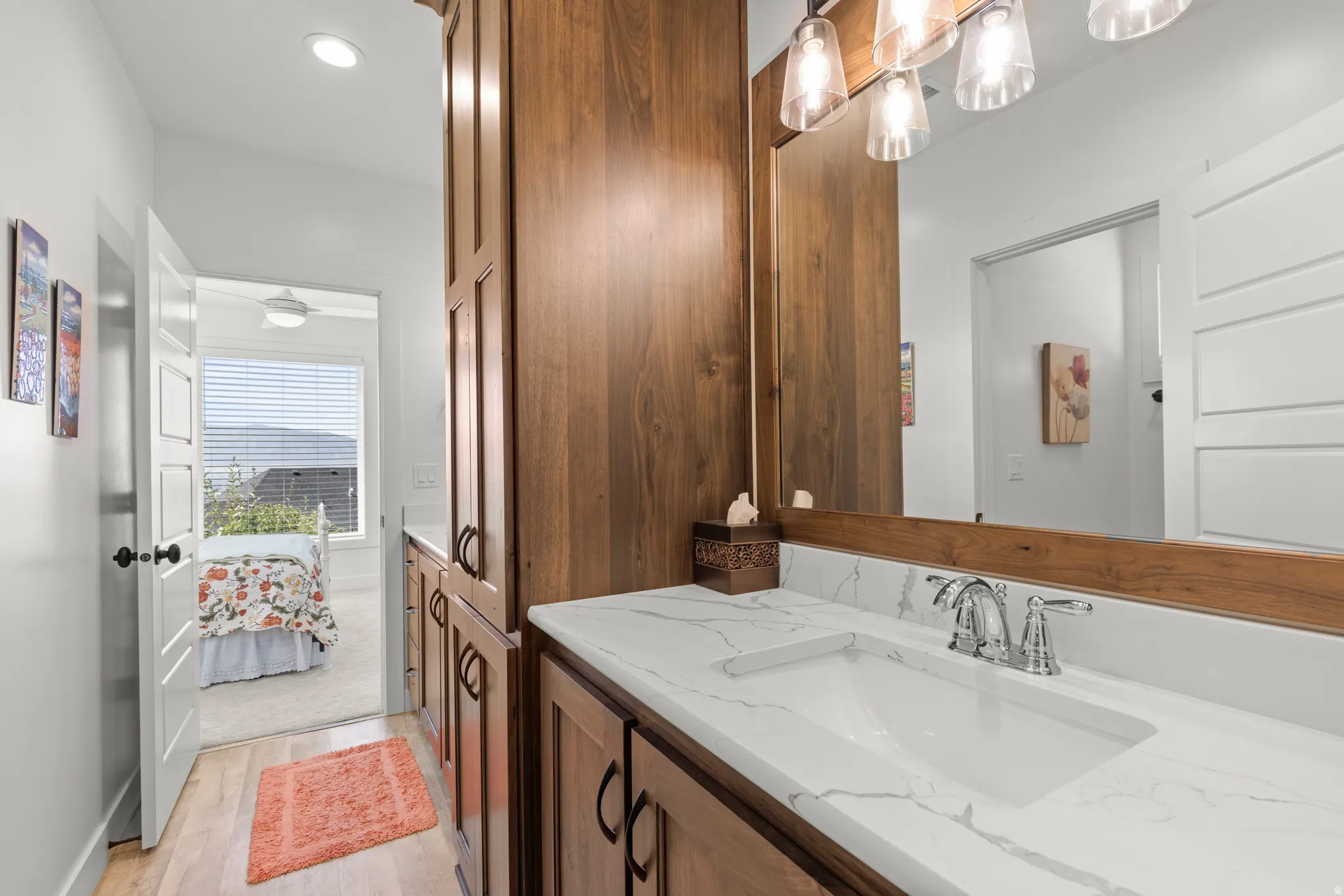 Bathroom vanity featuring a single undermount sink with chrome fixtures, a polished countertop, and a large wall-mounted mirror
