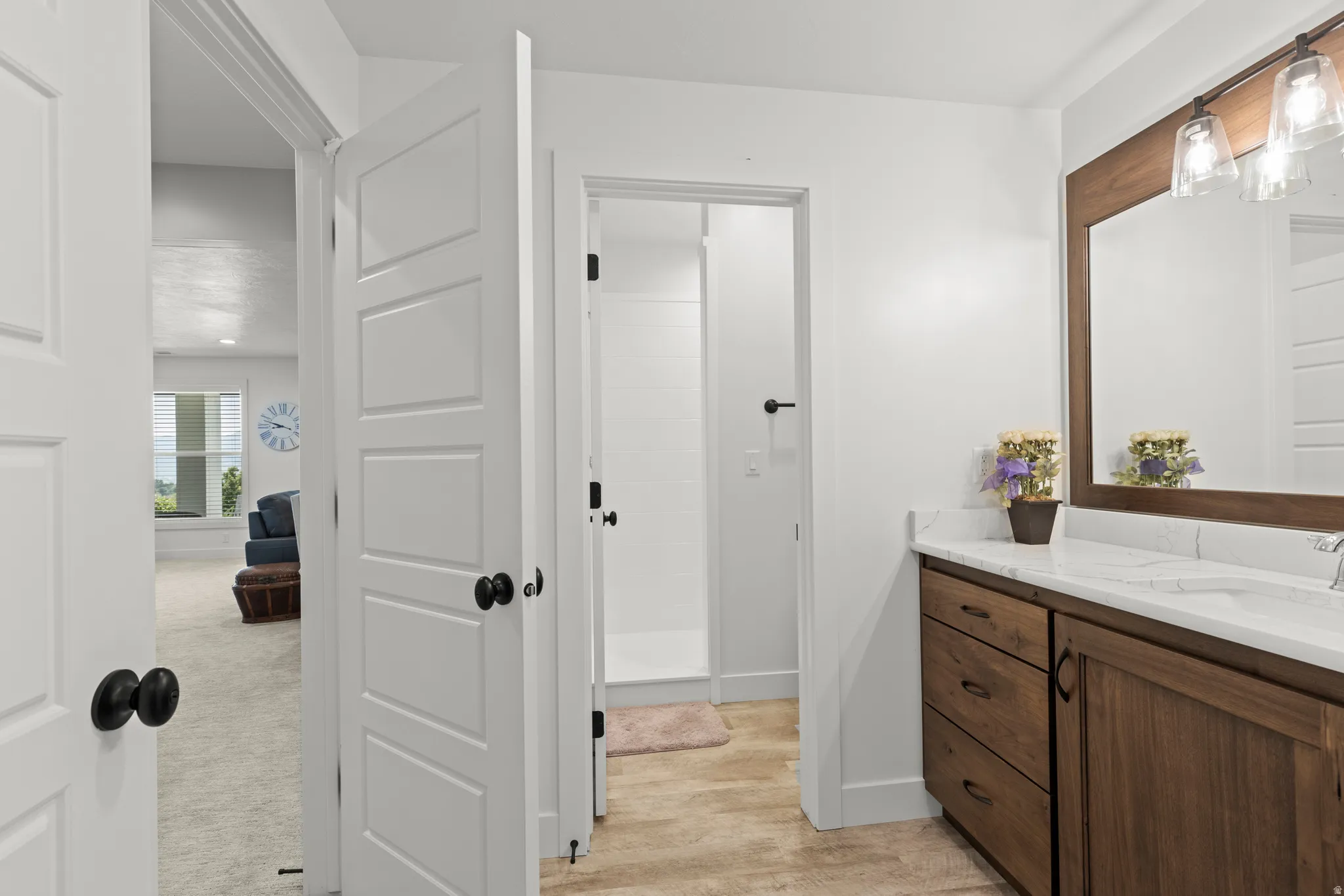 Bathroom vanity featuring wood cabinetry, white countertop with integrated sink, and an overhead mirror with a wood frame and glass sconce lighting