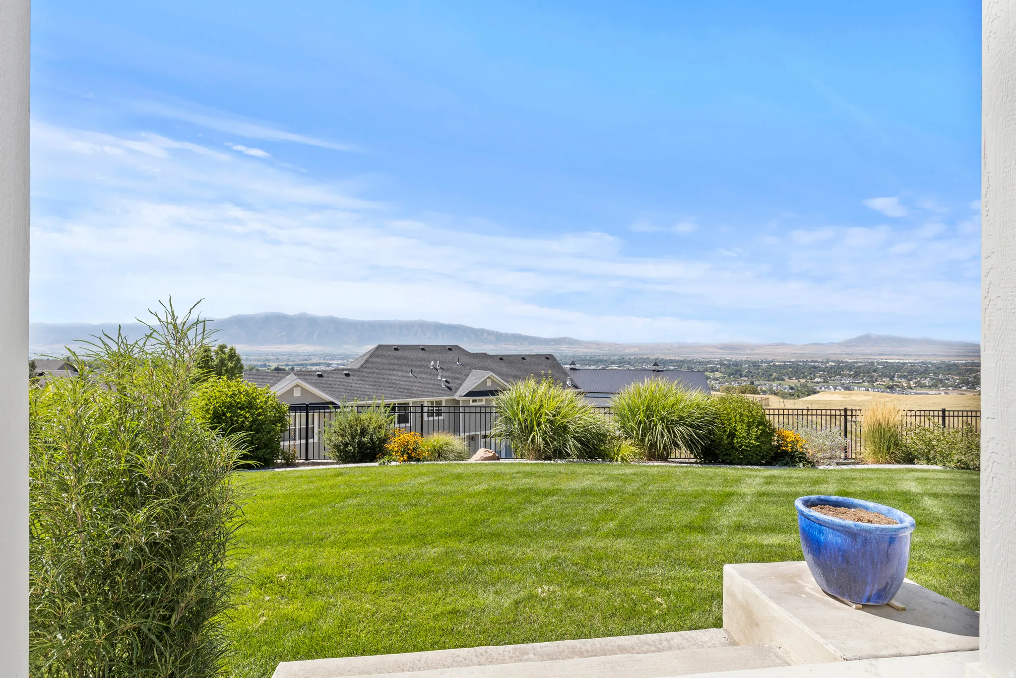 Expansive backyard featuring a manicured lawn, established landscaping, and a distant mountain range